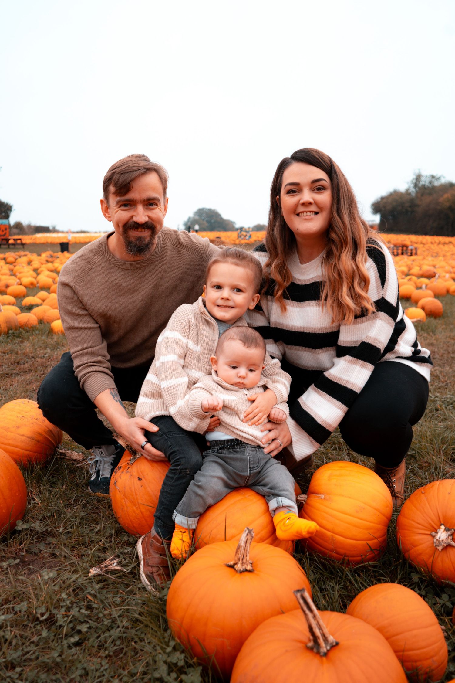 Family enjoying a fall day together at a pumpkin patch.