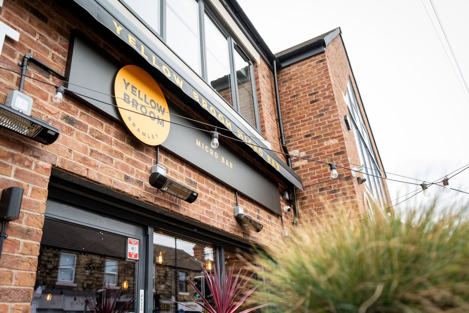 Modern brick building exterior with gray planter boxes and commercial signage.