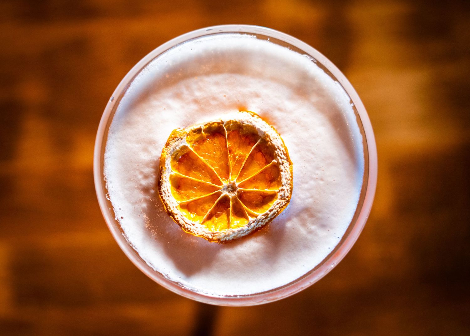 Cocktail glasses garnished with dried orange slices in warm lighting.