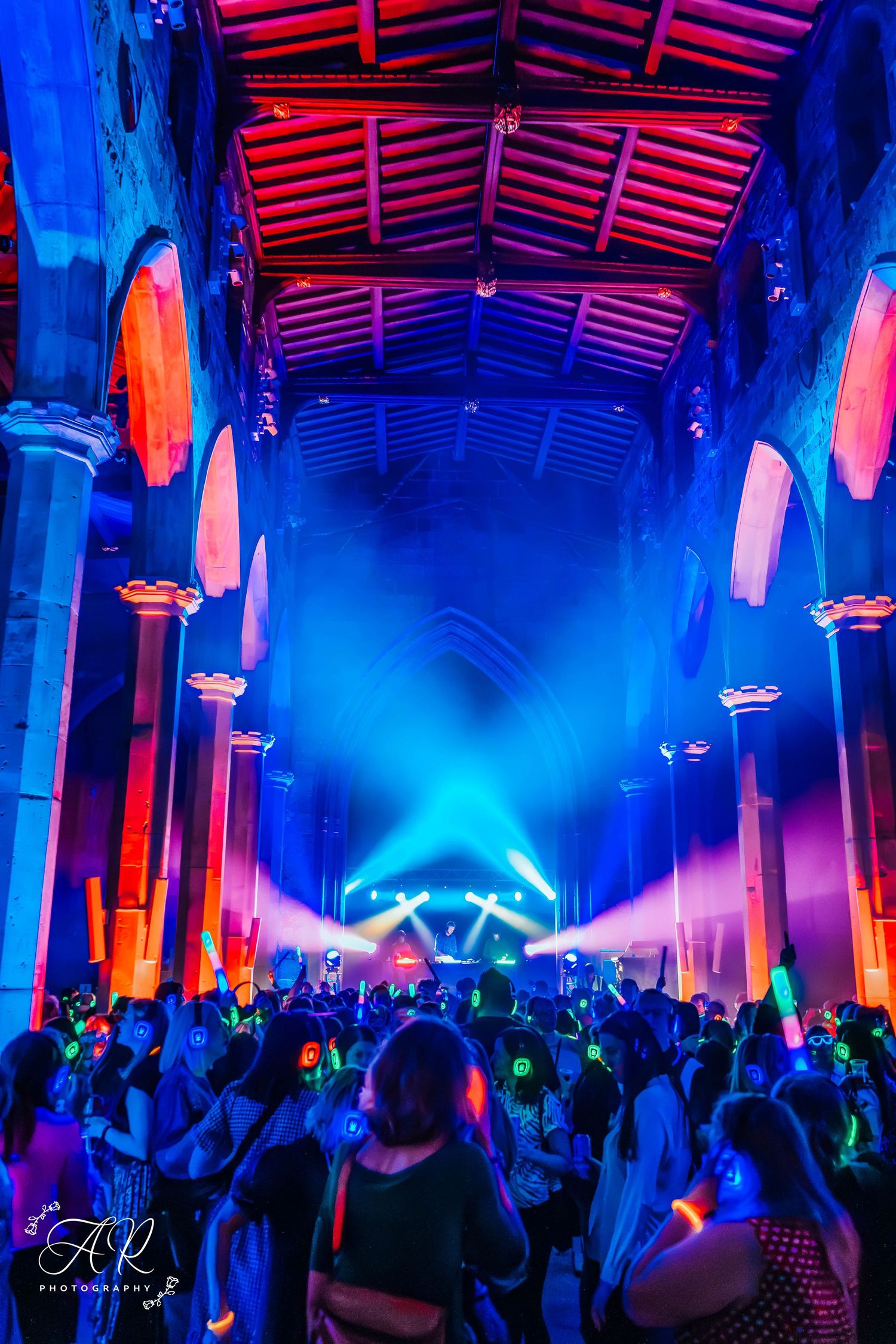 Large indoor venue illuminated with dramatic blue and red lighting during an electronic music event.