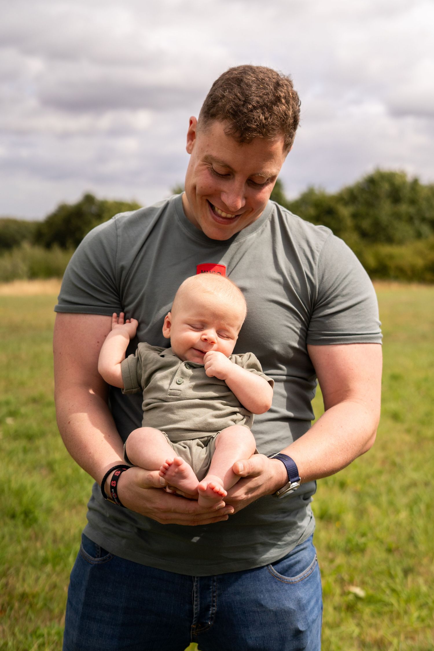 Playful moments with a baby wearing gray clothing in a summer field.