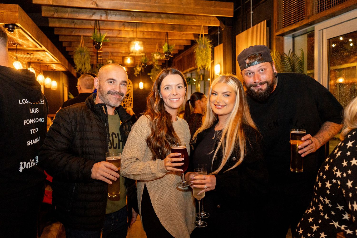 Groups of patrons socializing and celebrating at a cozy pub with wooden decor.
