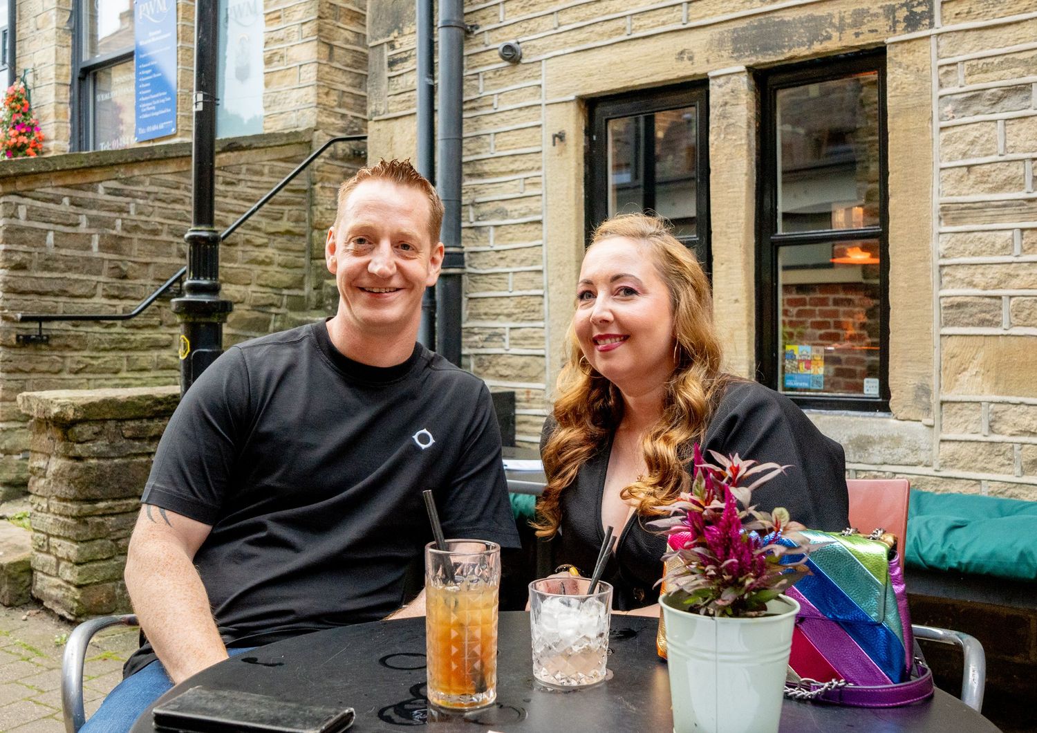 Group gathered at a casual outdoor dining area with stone walls and drinks on the table.