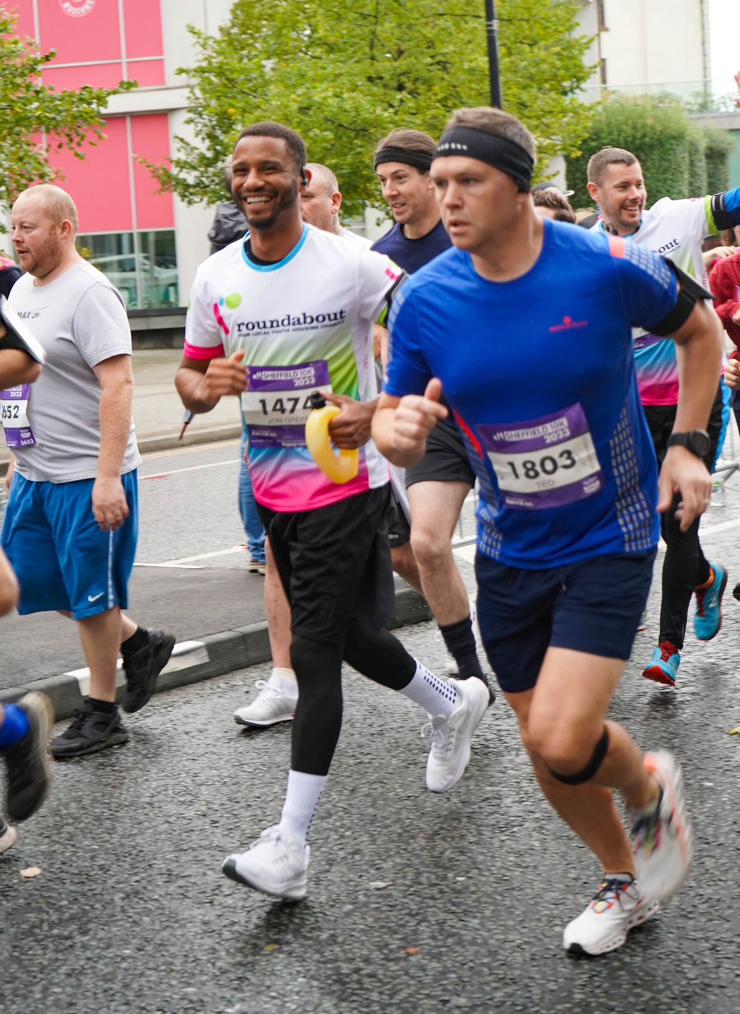 Runners in athletic gear competing during a rainy charity road race event.