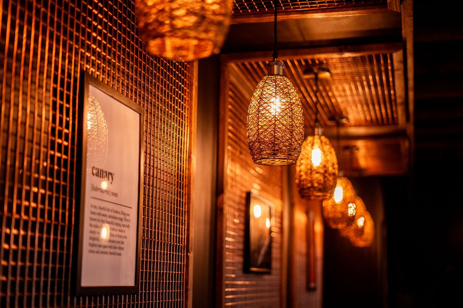 Atmospheric corridor with woven pendant lights creating warm ambiance against textured walls.