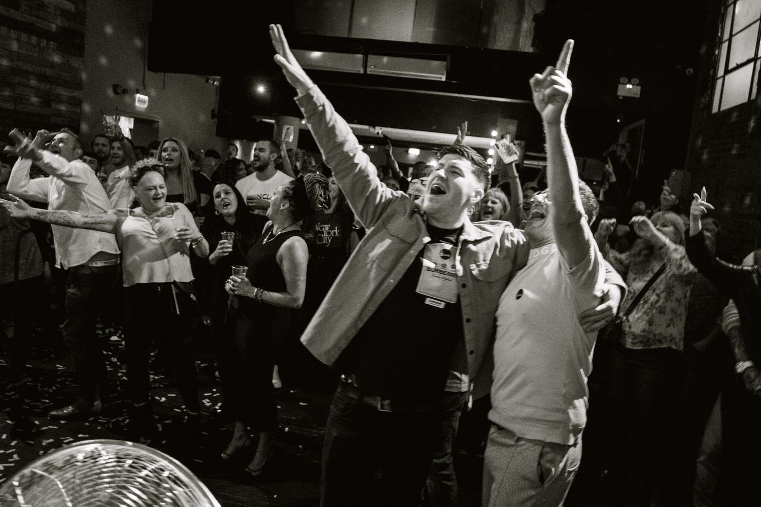 Black and white shot of concert audience with raised hands during an energetic performance.