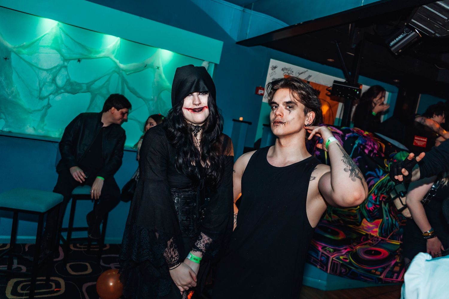 People socializing at a nightclub with teal ambient lighting and dark atmosphere.