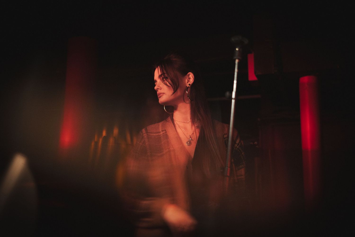 A performer bathed in atmospheric red stage lighting during a show.