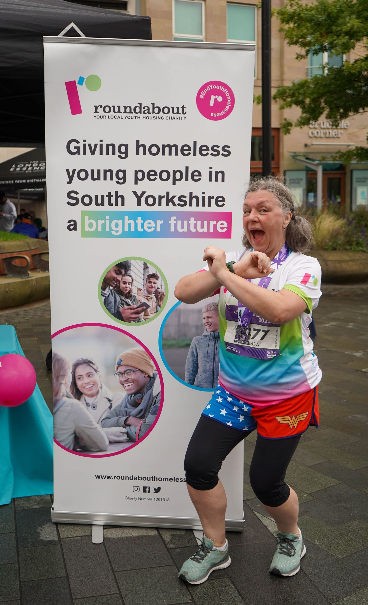 Enthusiastic runner poses with Roundabout charity banner at fundraising event.