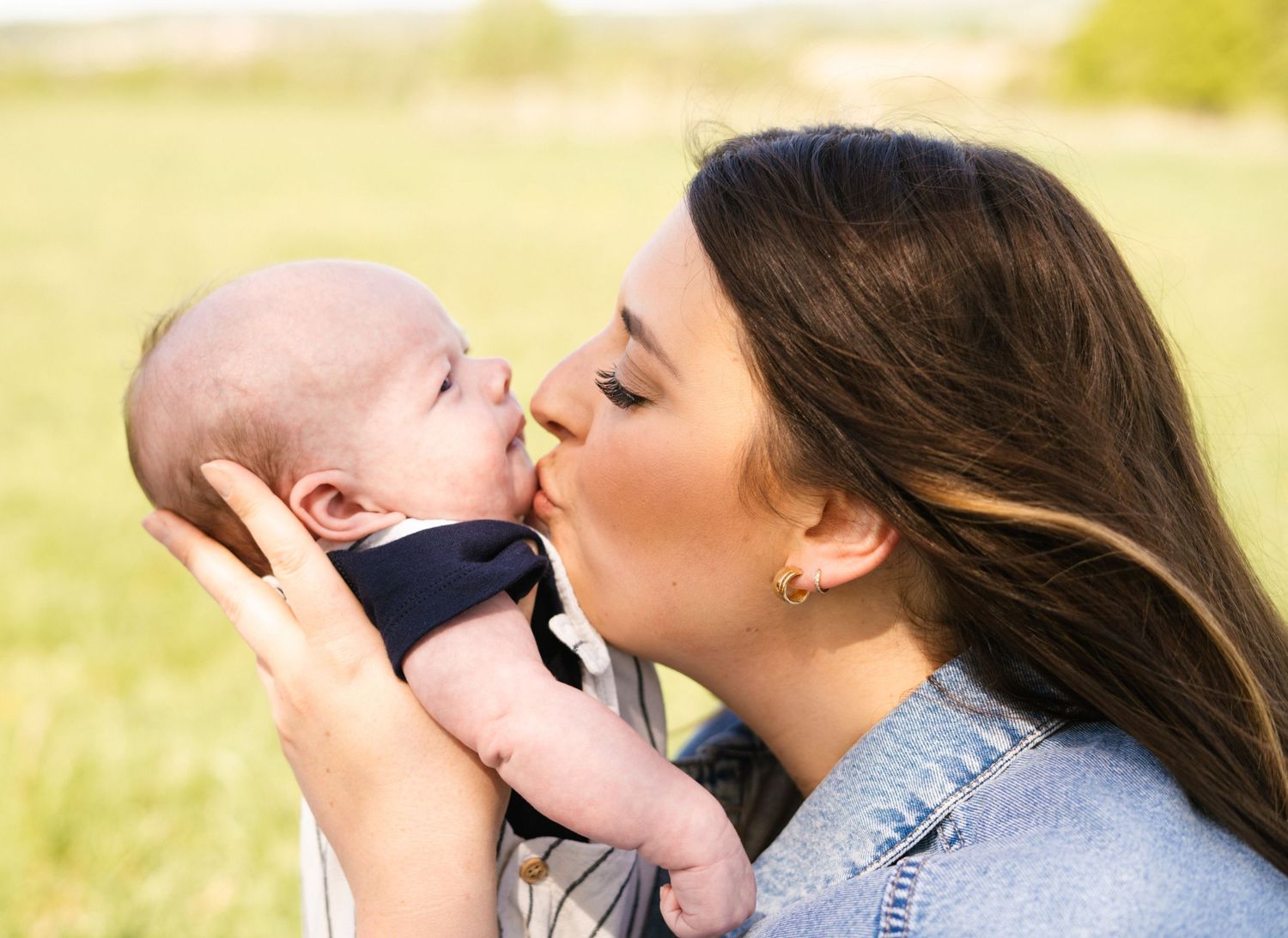 A tender outdoor family moment showing affection and bonding in natural lighting.