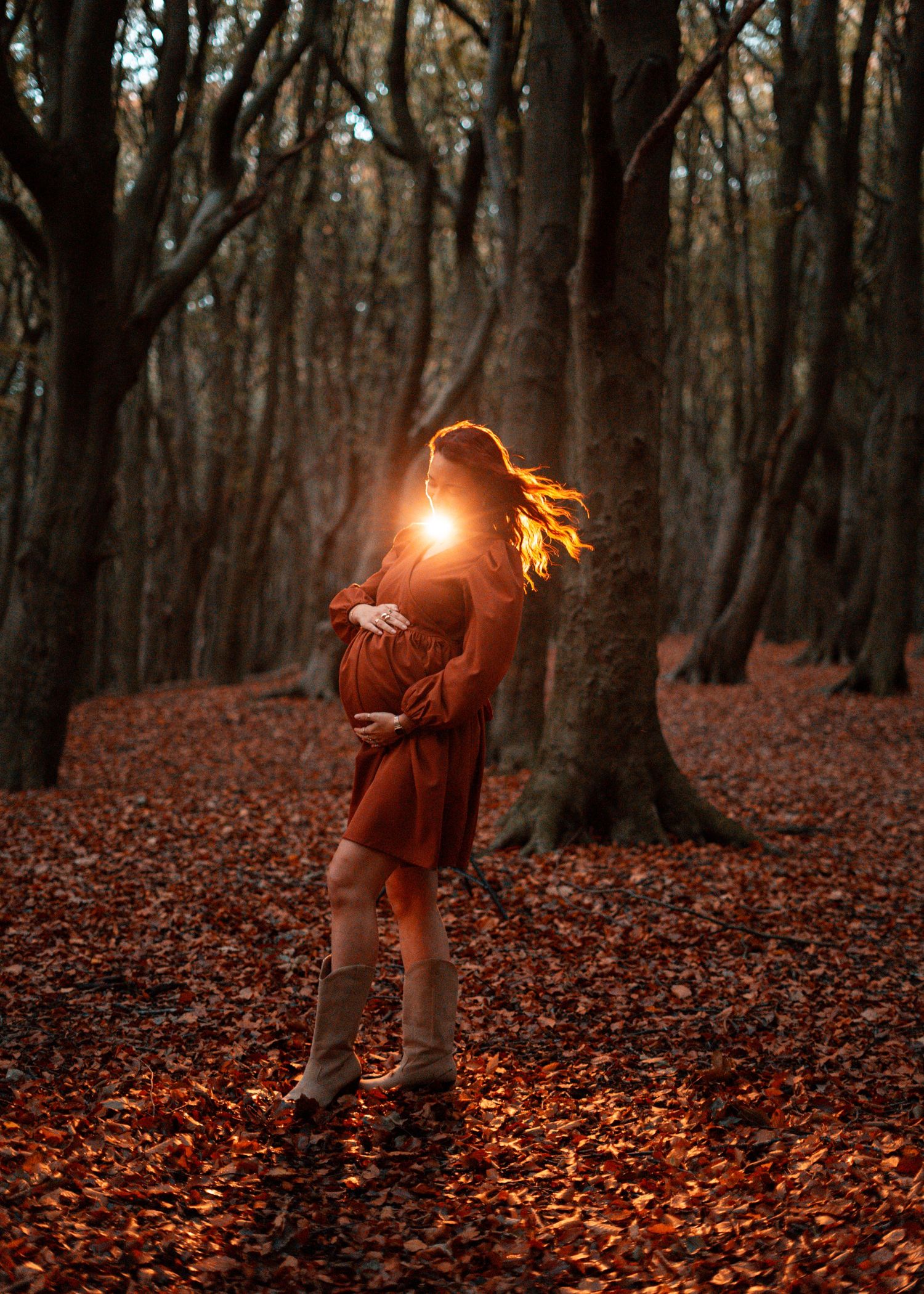 Ethereal forest photoshoot with glowing light effects and figure in red dress.