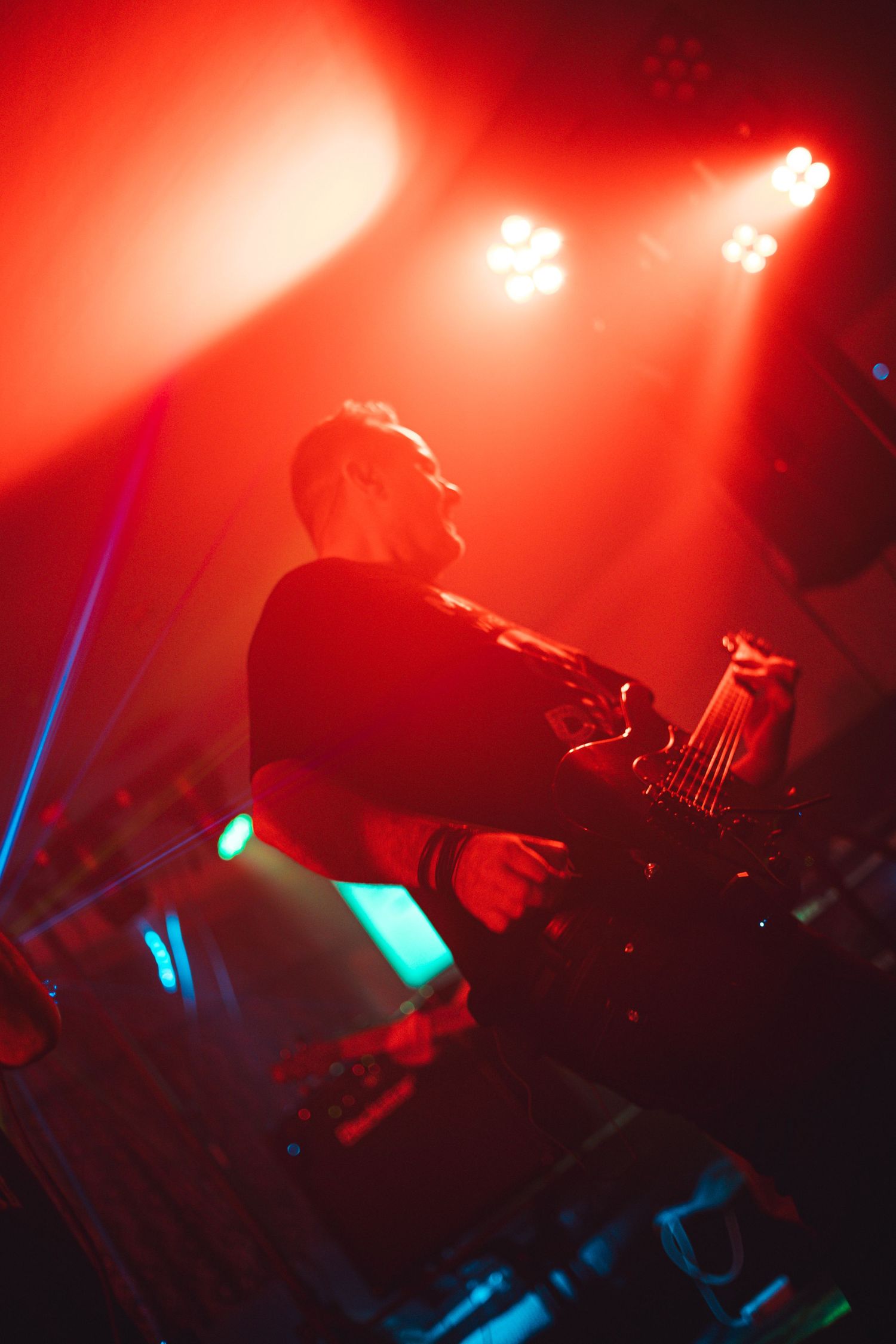 Musician silhouetted against intense red stage lighting while performing.