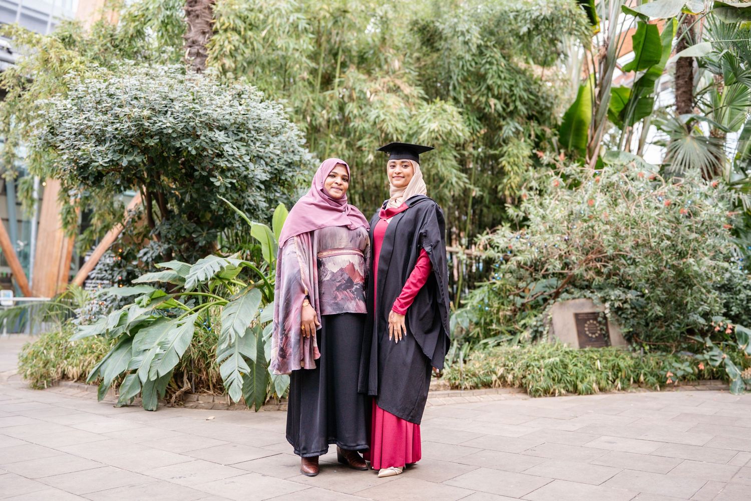 A graduation celebration in a lush garden setting with graduates in traditional academic regalia.