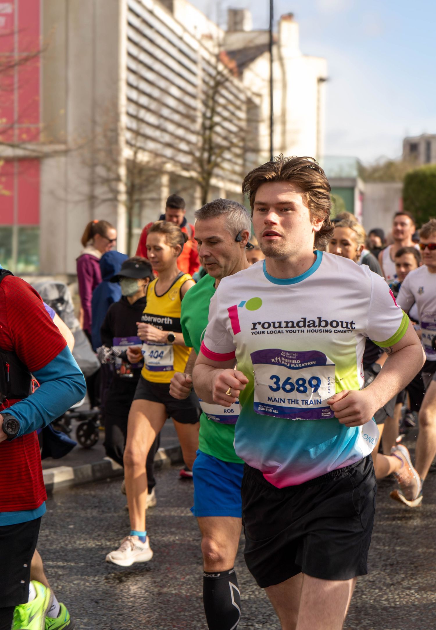 Runner wearing Roundabout charity shirt participates in urban marathon event.