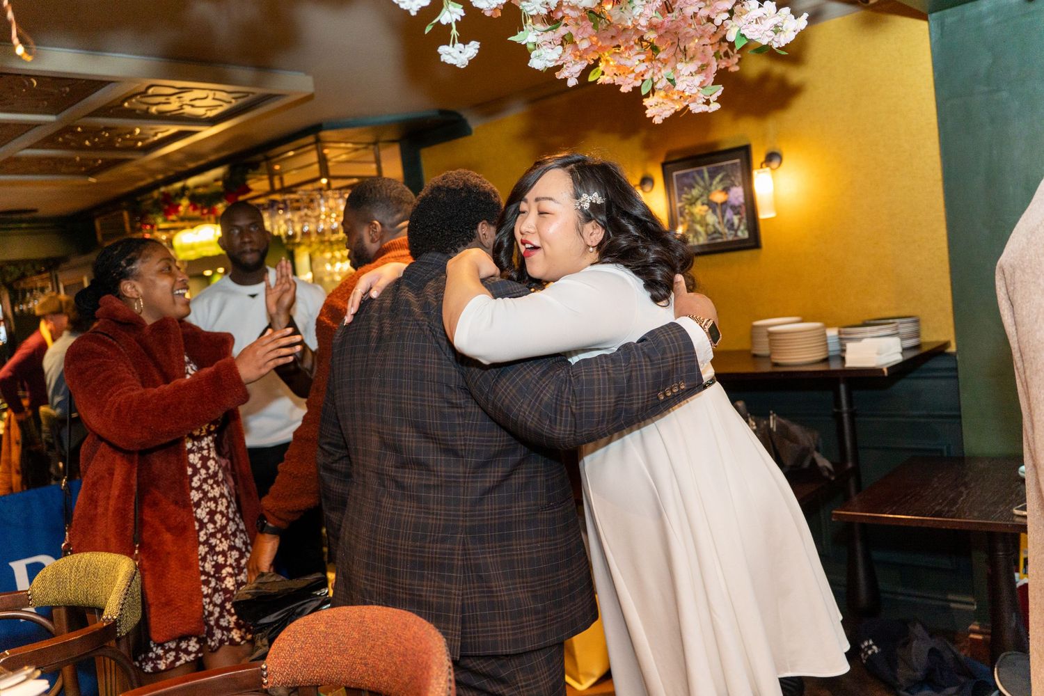 Celebration in a venue decorated with cherry blossoms and ambient lighting.