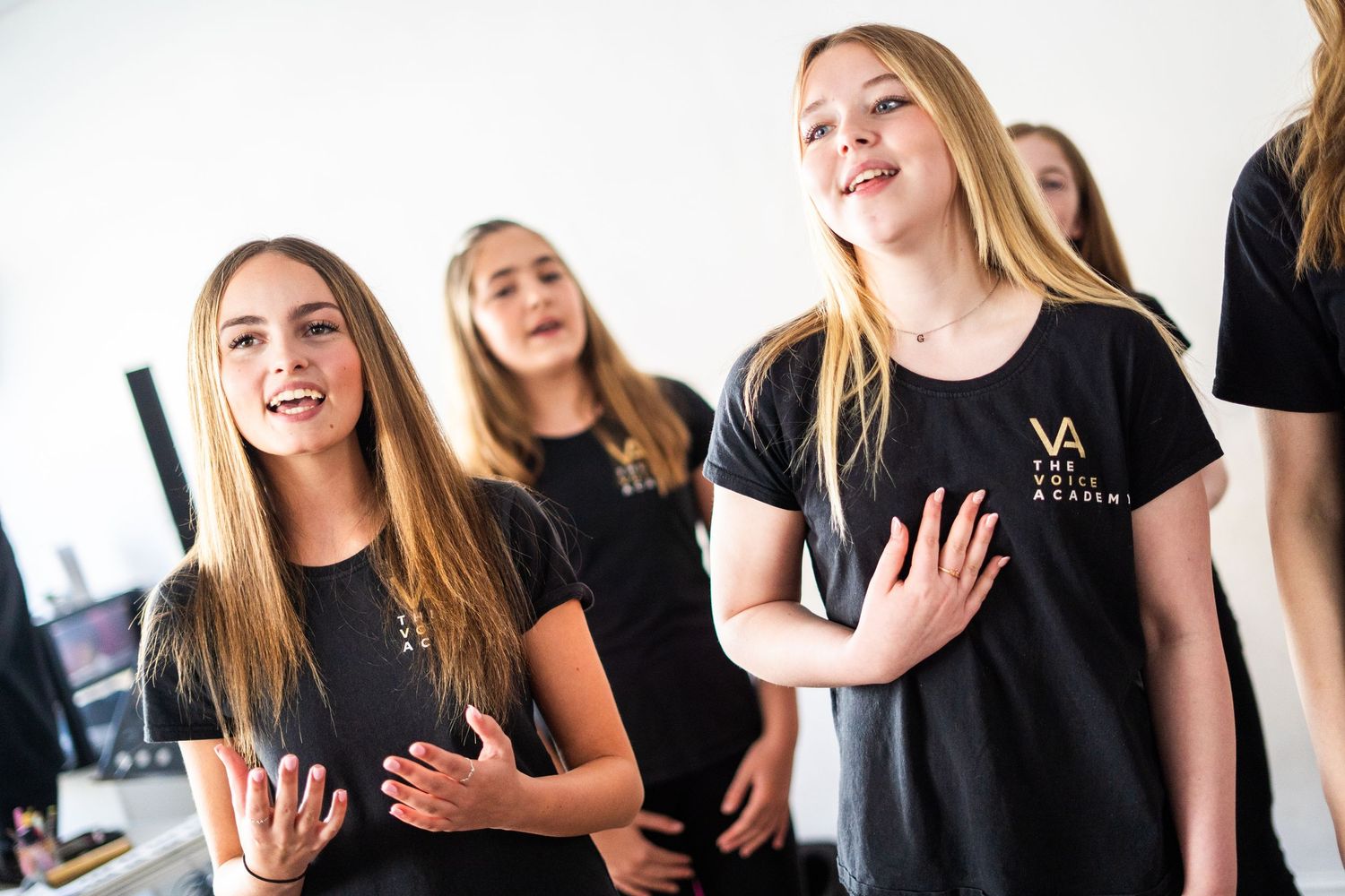 Performers in matching black uniforms practicing vocal harmonies together.