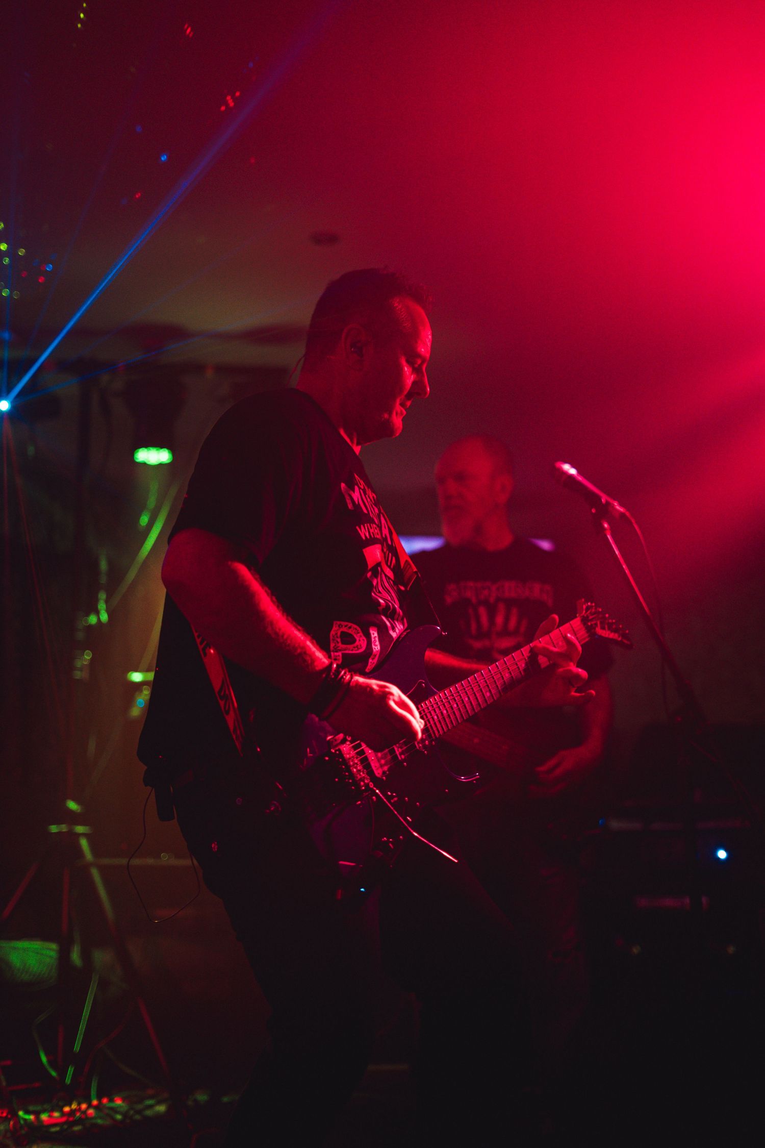 Guitar player performs under dramatic red stage lighting during live show.