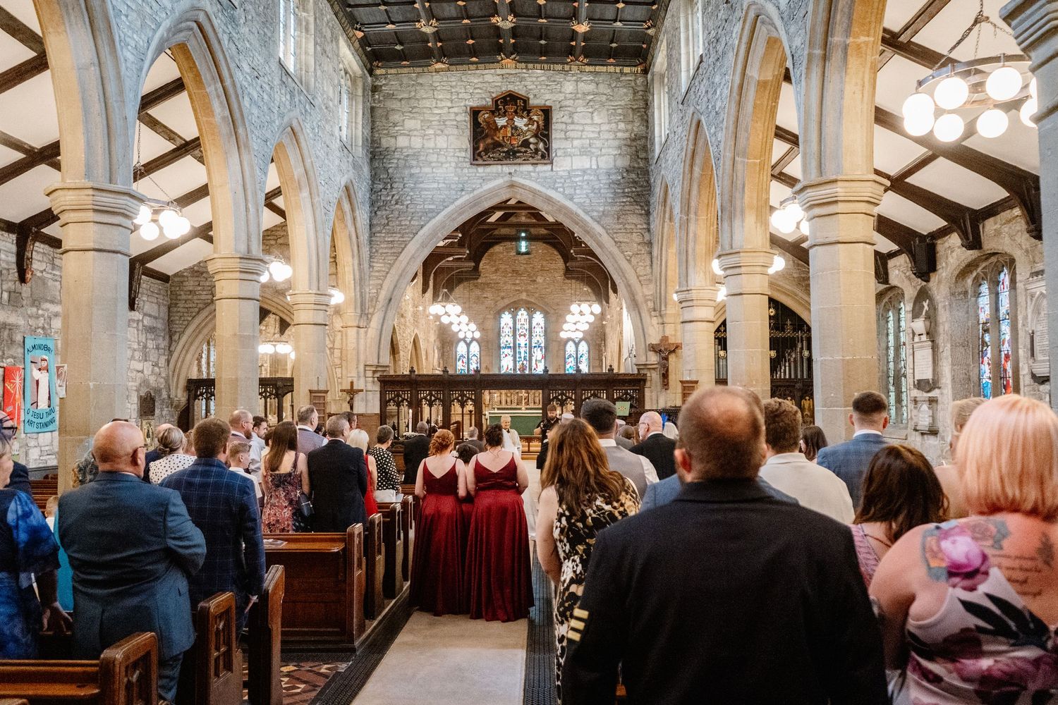 Interior view of a traditional church during a wedding ceremony with ornate gothic architecture and stained glass windows.