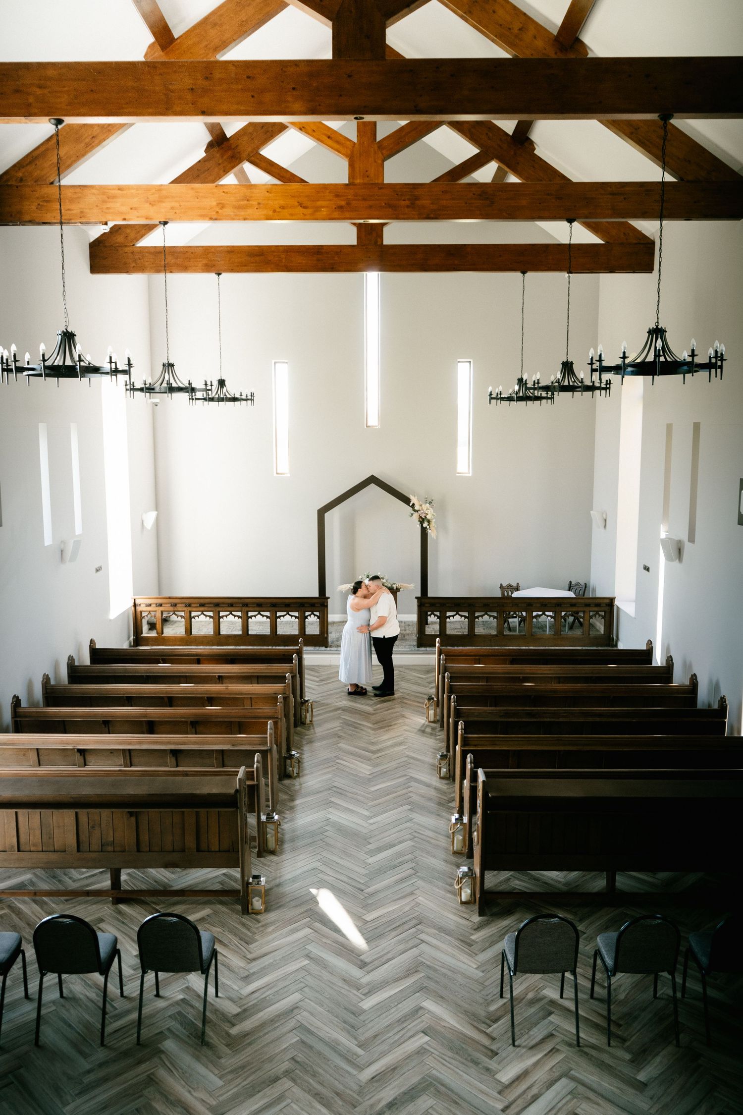 Modern chapel interior with exposed wooden beams and natural light streaming through vertical windows.