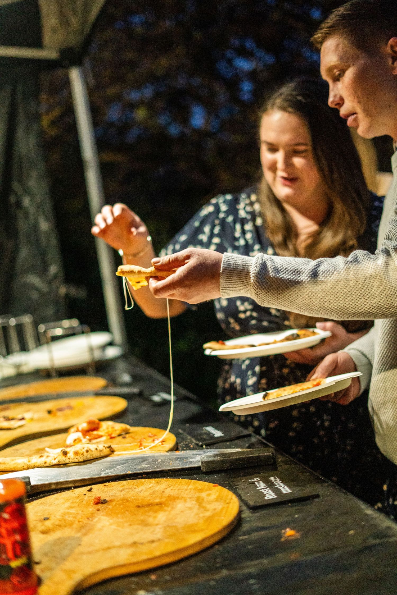 Close-up view of pizza being served on wooden boards at a restaurant.