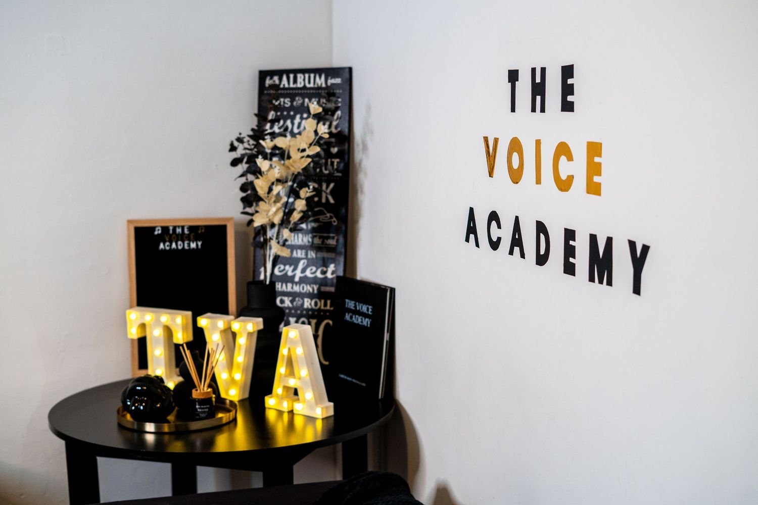 Decorative display featuring 'THE VOICE ACADEMY' signage with black and gold elements.