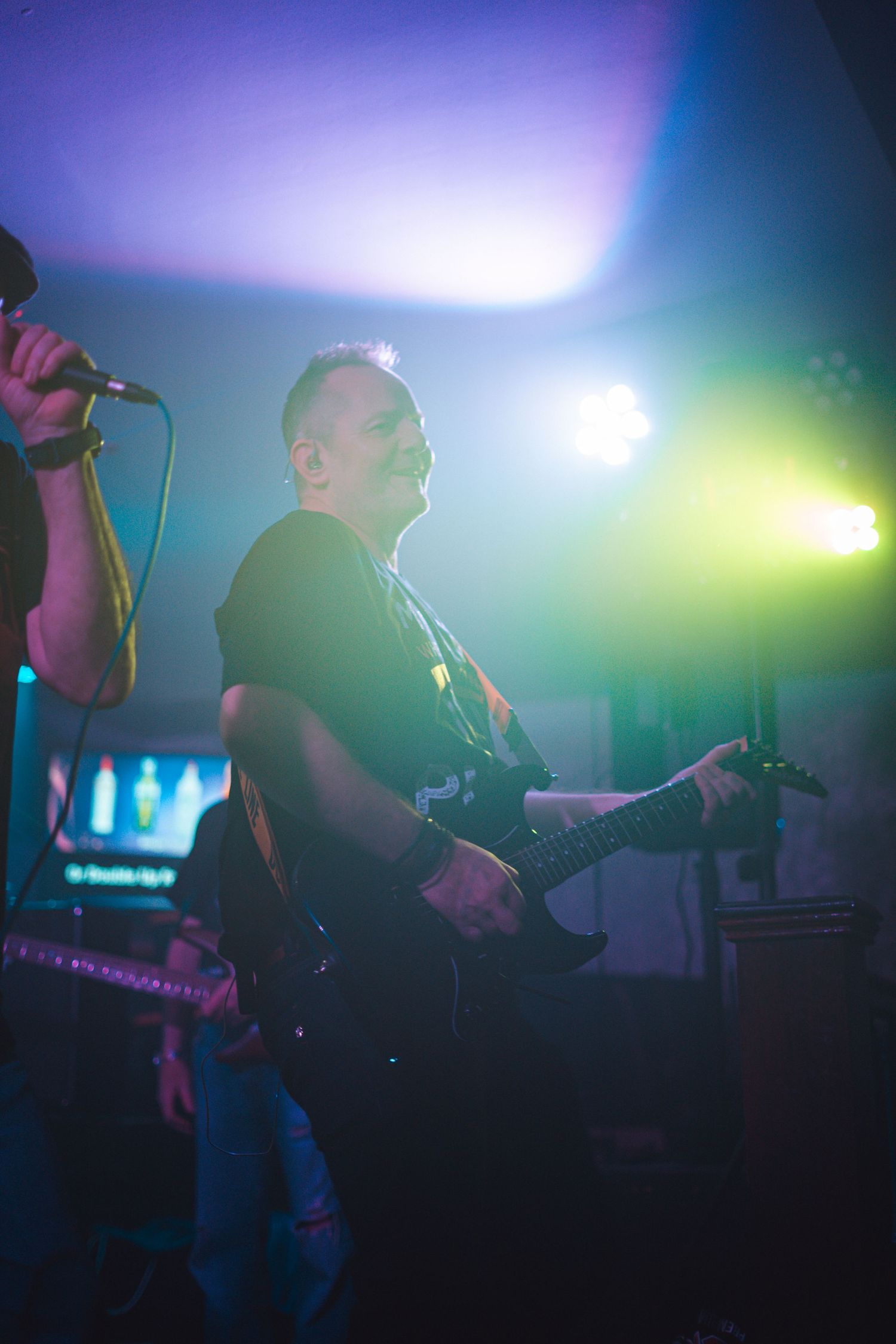 Musicians performing on stage with colorful ambient lighting effects.