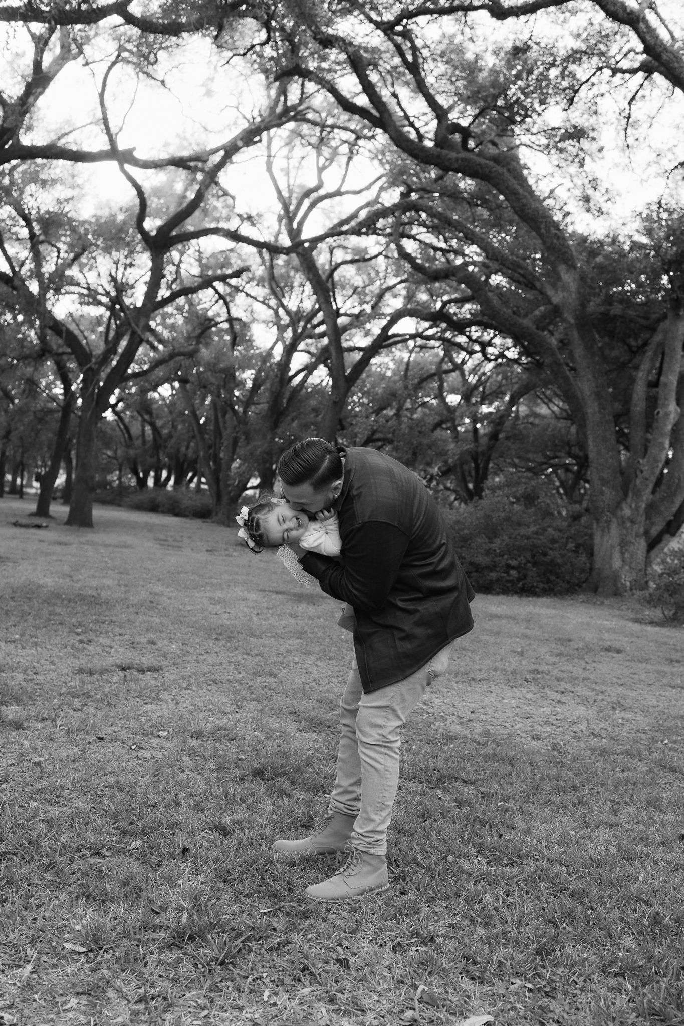 A black and white portrait of a tender moment in a park setting.