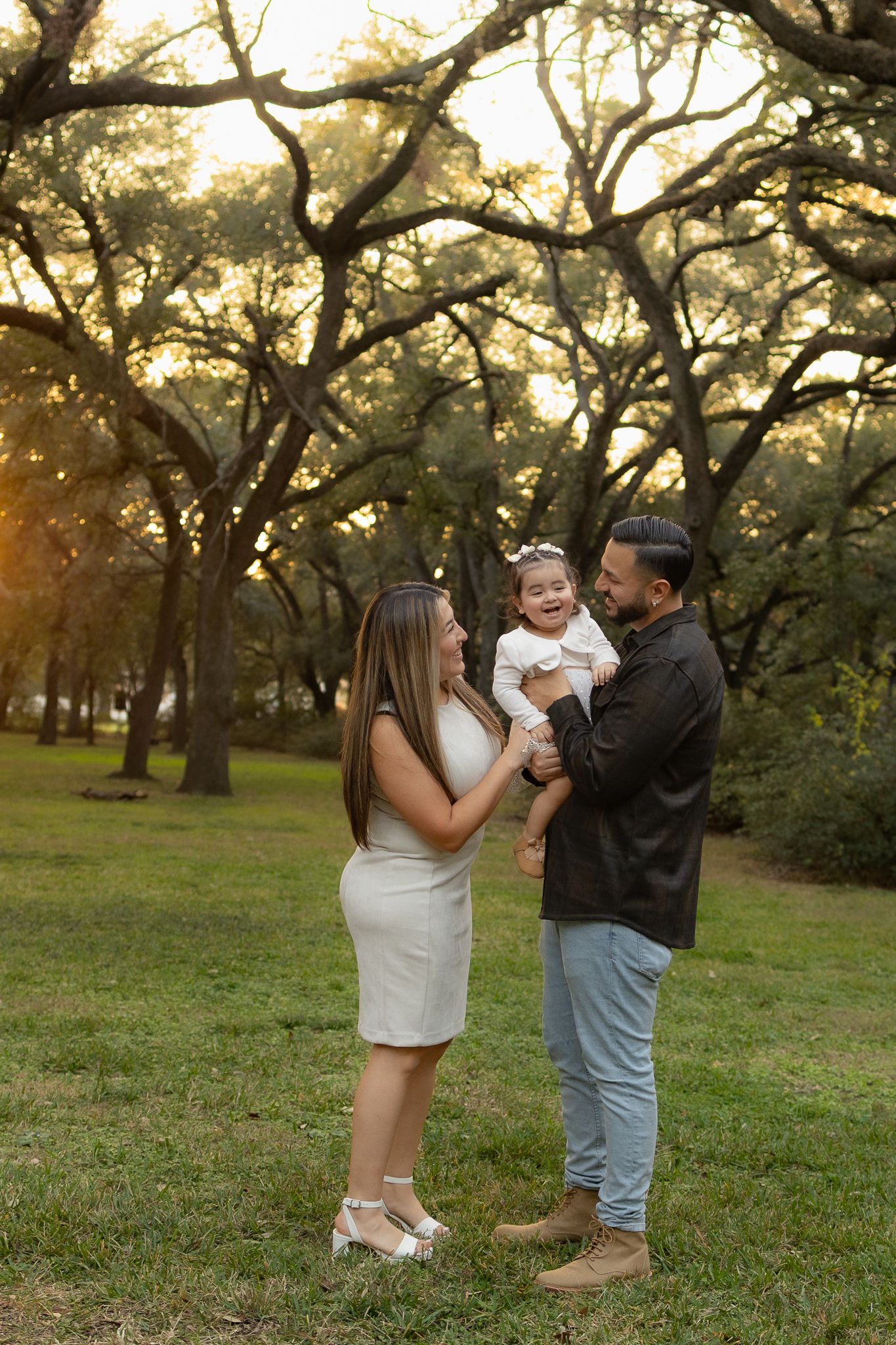 A family shares a joyful moment together in a park during golden hour.