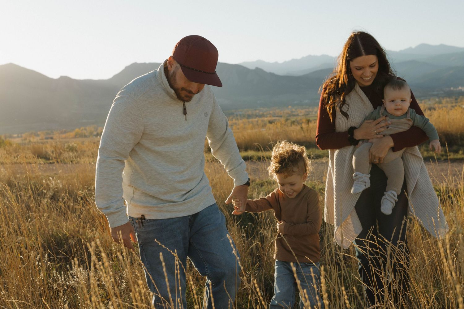 Family of four walking together through a Colorado mountain meadow during a warm and natural family photography session