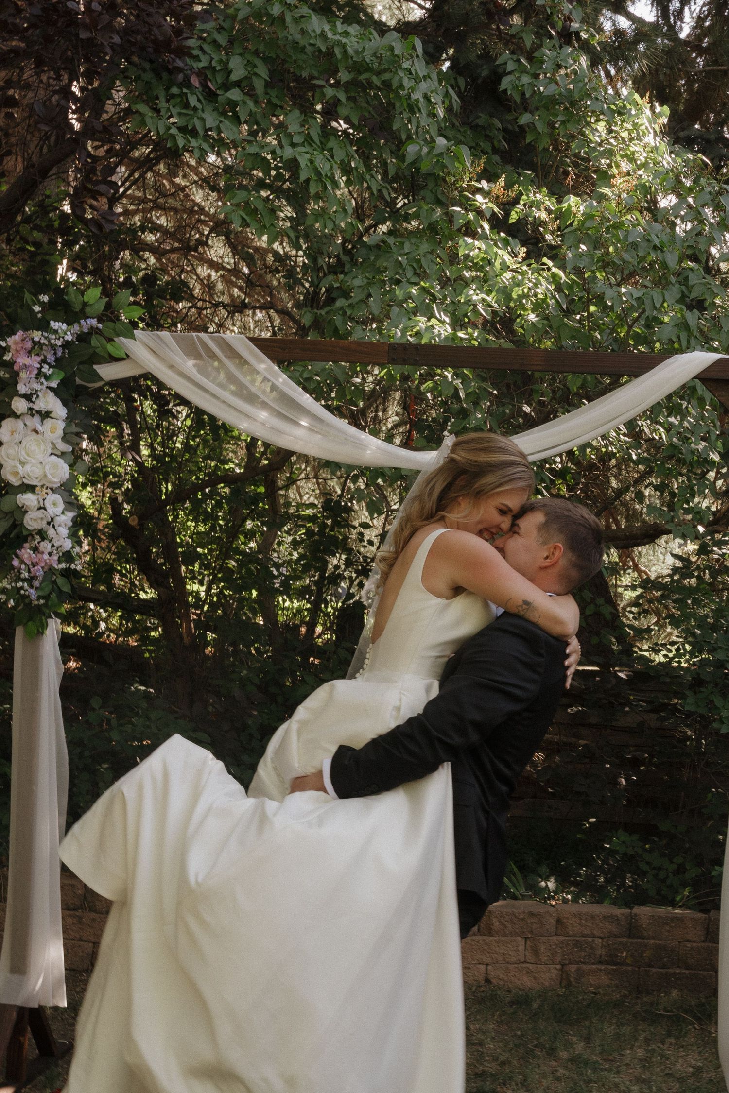 Bride and groom sharing a joyful moment beneath a wedding arbor