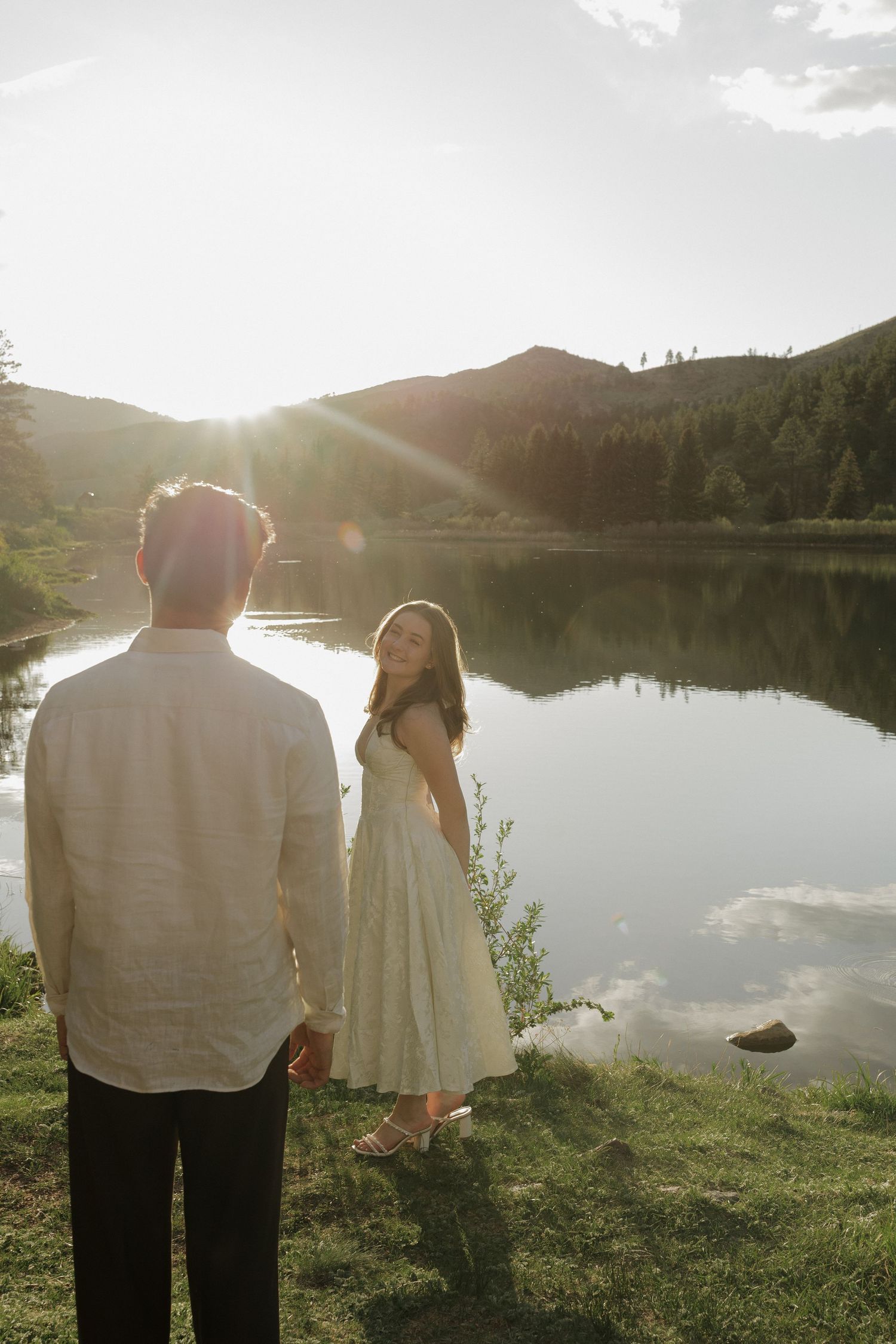 Couple standing together beside a mountain lake at golden hour during an intimate outdoor couples photography session