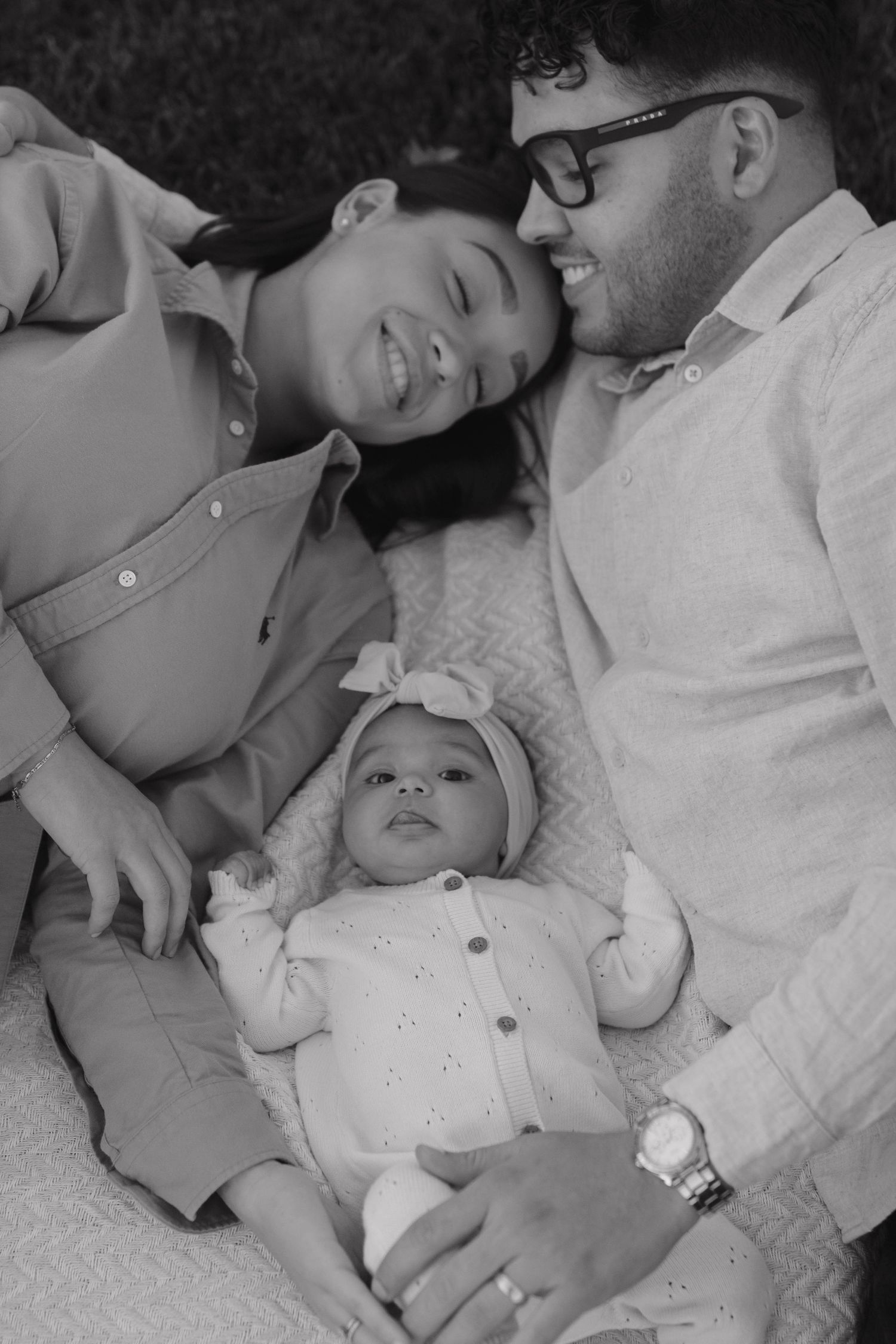 Parents cuddling with their newborn baby in a tender black and white maternity photograph