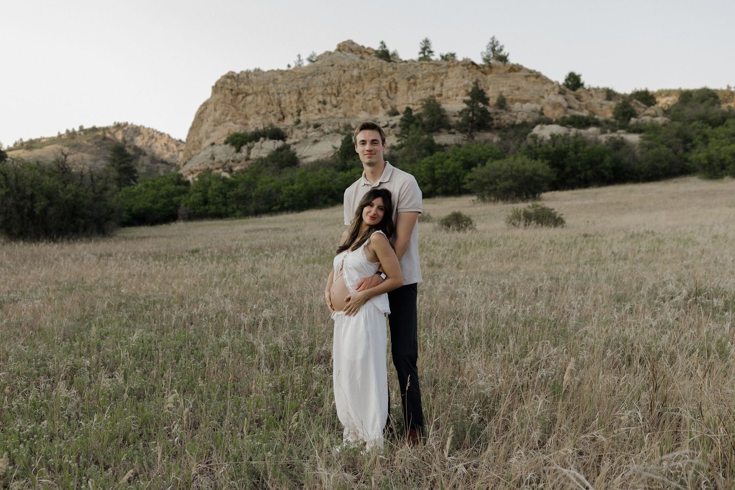 Expecting couple embracing in a natural outdoor setting during an intimate maternity photography session