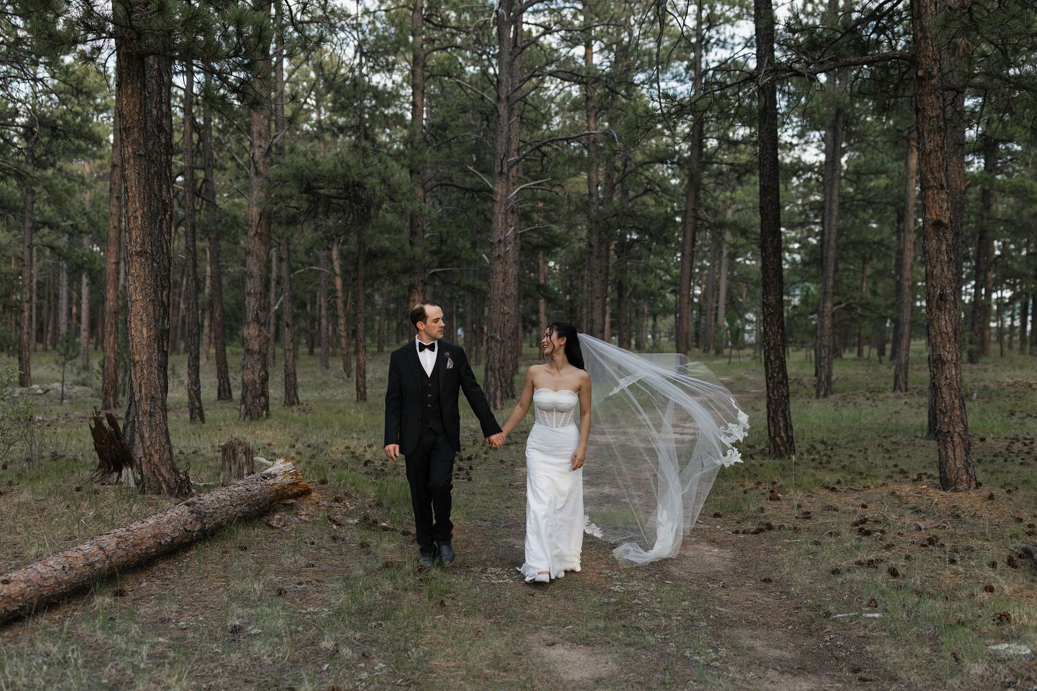 Bride and groom walking together through a forest on their wedding day, captured in a natural and romantic style