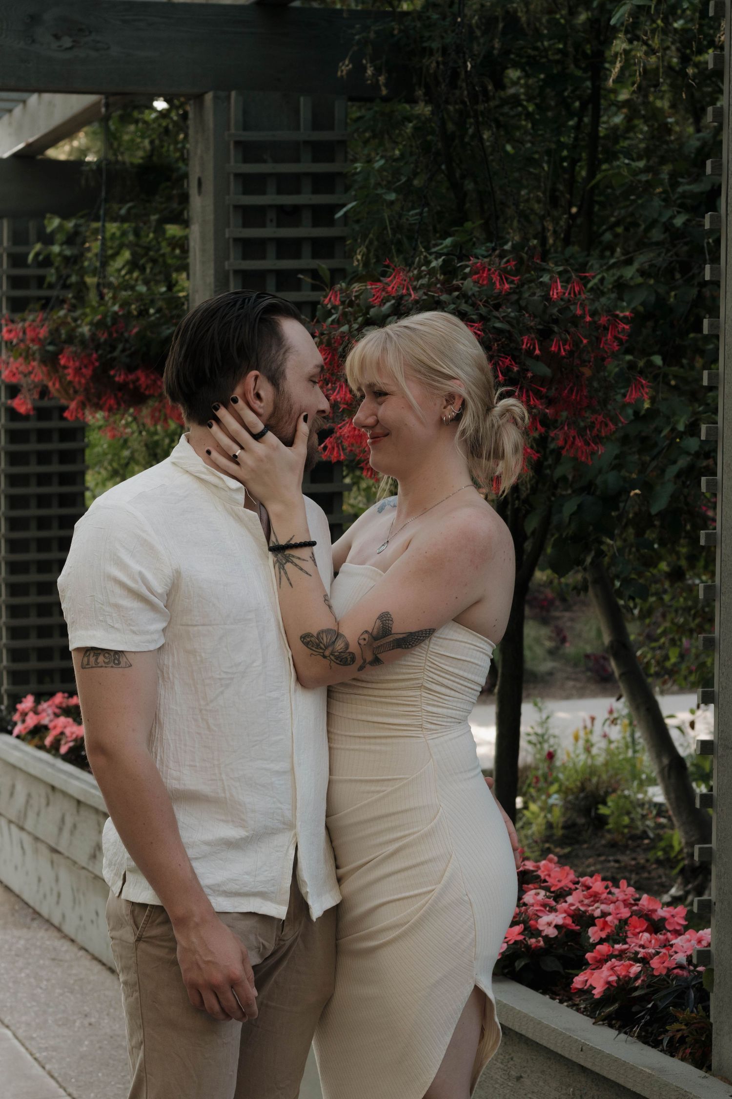 Couple sharing a kiss outdoors surrounded by lush greenery during an intimate couples photography session