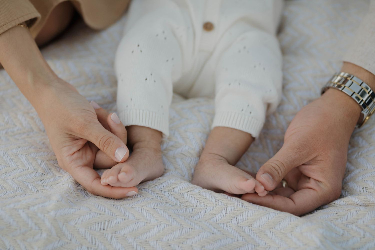 Close-up of a newborn baby’s tiny hands held gently by both parents during a maternity photography session