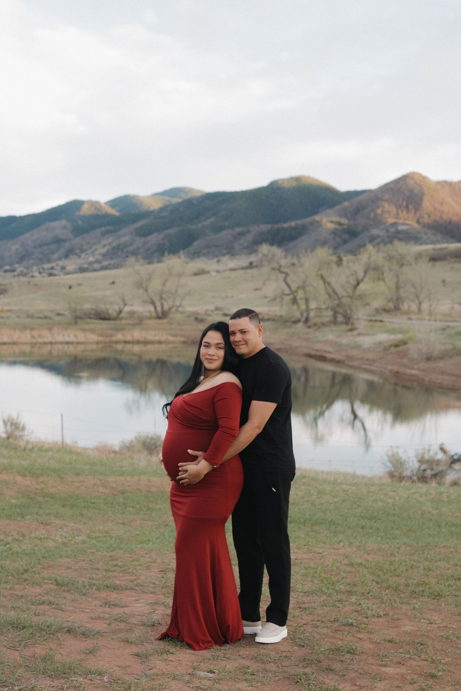 Expecting couple embracing beside a Colorado lake during a romantic outdoor maternity photography session