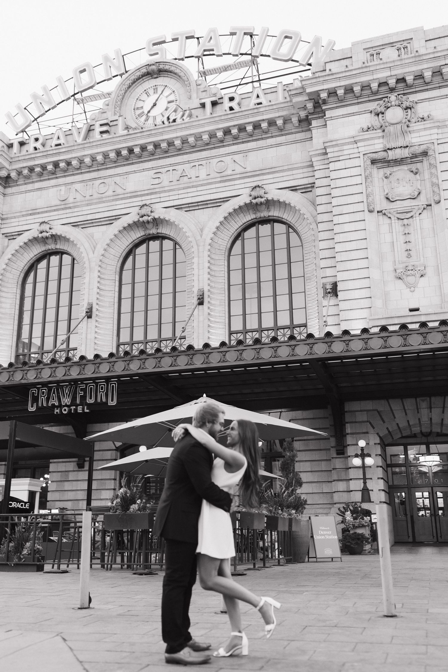 Black and white photo of a couple embracing and kissing outside Union Station