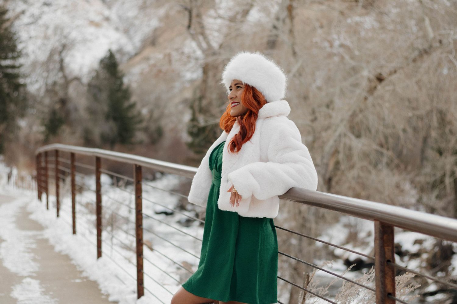 Woman posing in a white winter hat and green dress outdoors during a natural portrait photography session