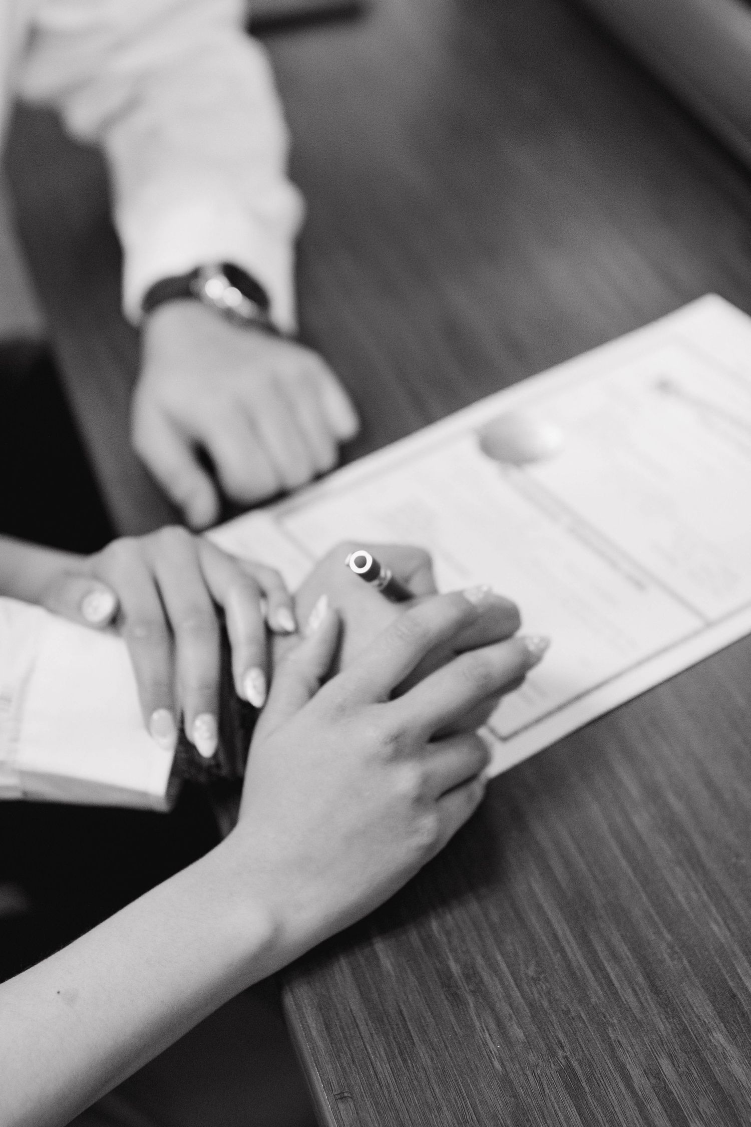 Close-up of hands signing documents during an intimate engagement celebration