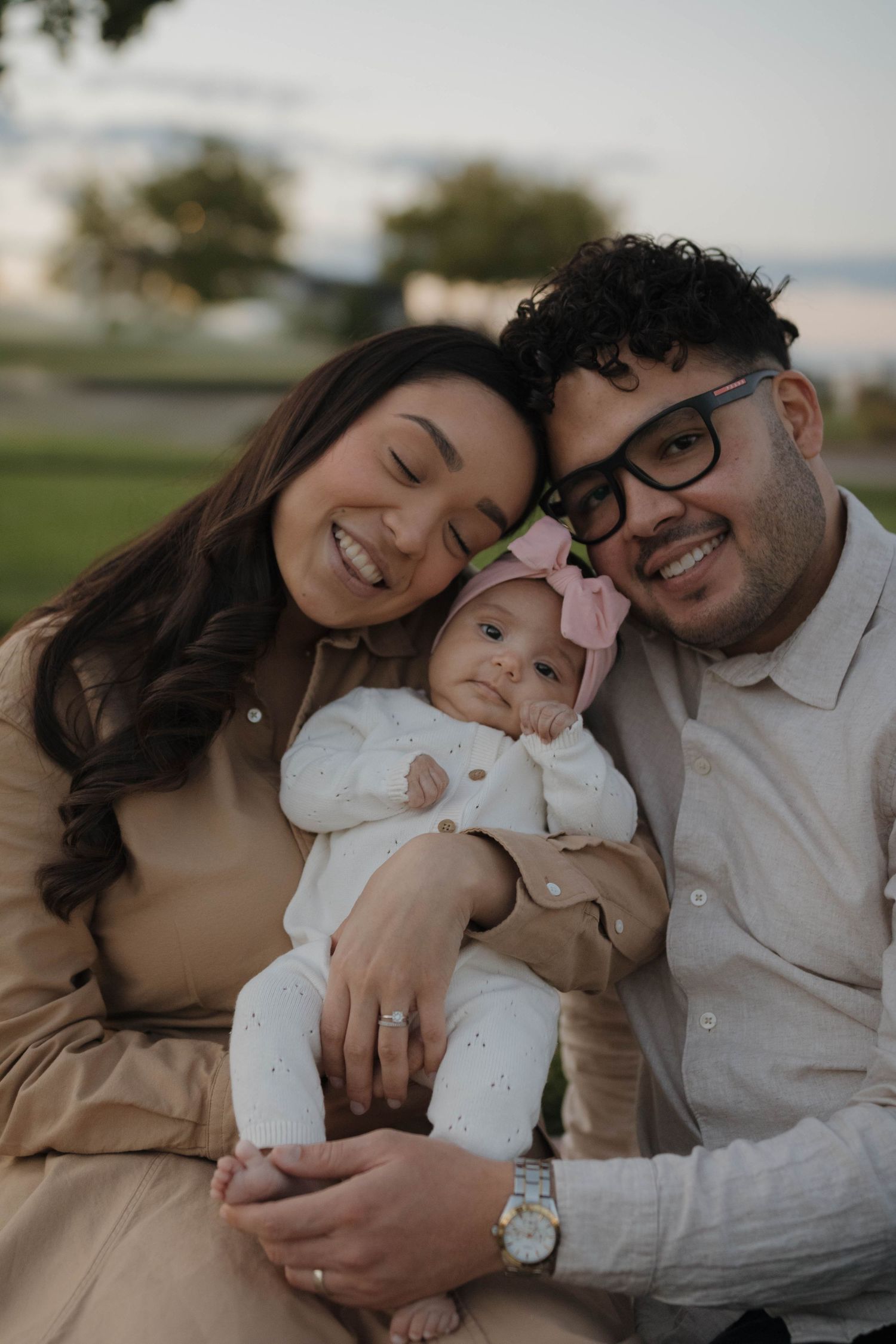 Expecting couple cuddling with their baby outdoors during a warm and intimate maternity photography session