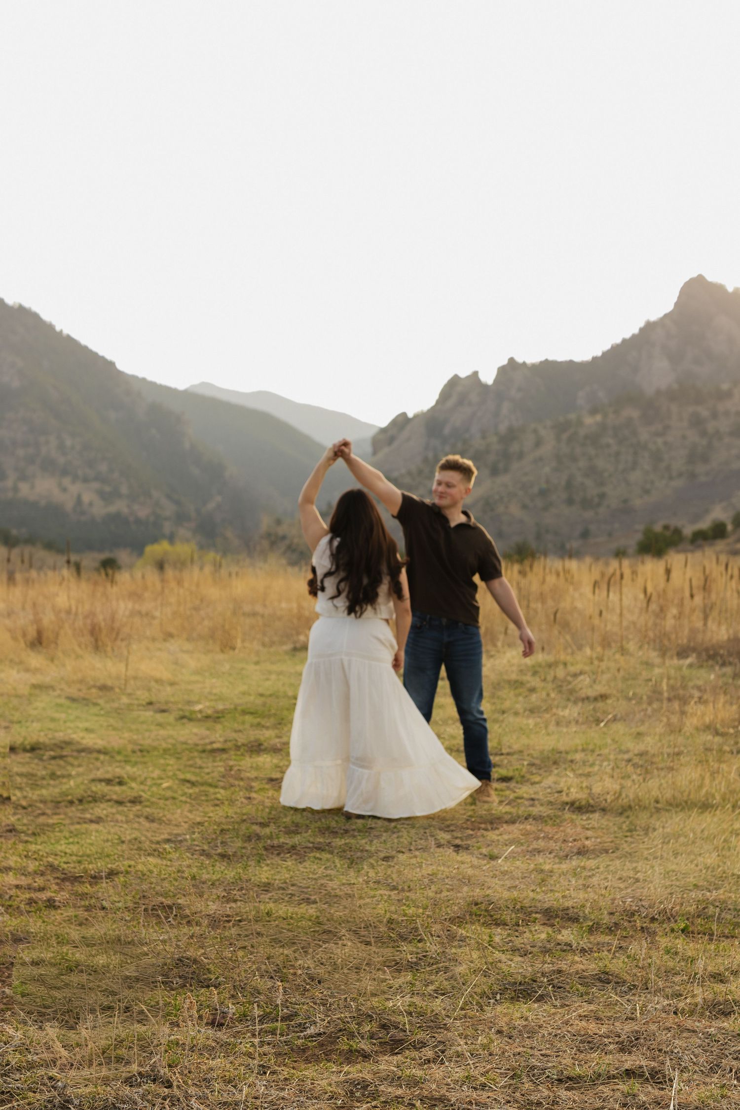 Expecting couple walking together through a mountain meadow during an intimate outdoor maternity photography session