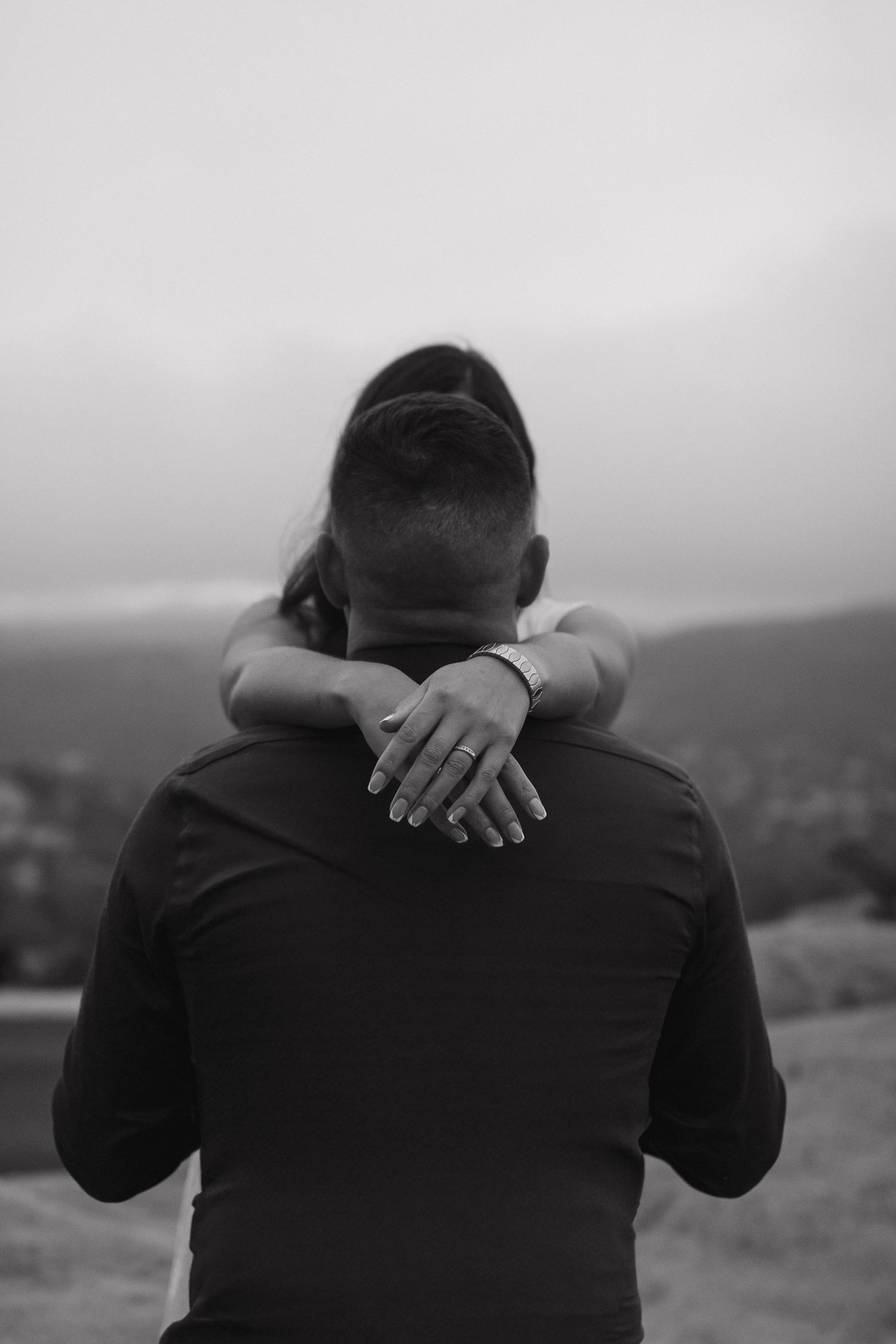 Couple sharing a tender embrace outdoors during an intimate black and white couples photography session