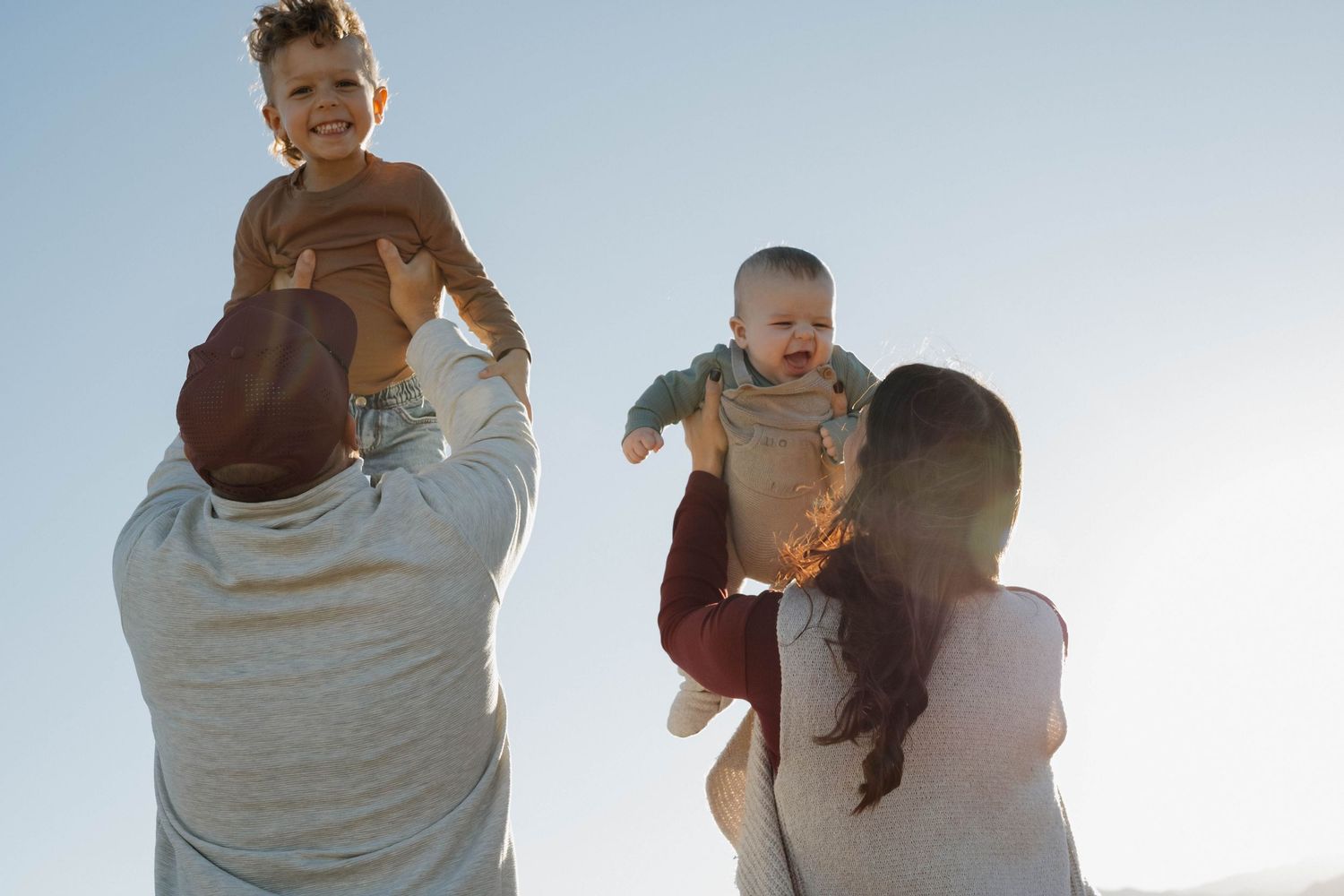 Parents lifting and playing with their children outdoors during a joyful family photography session