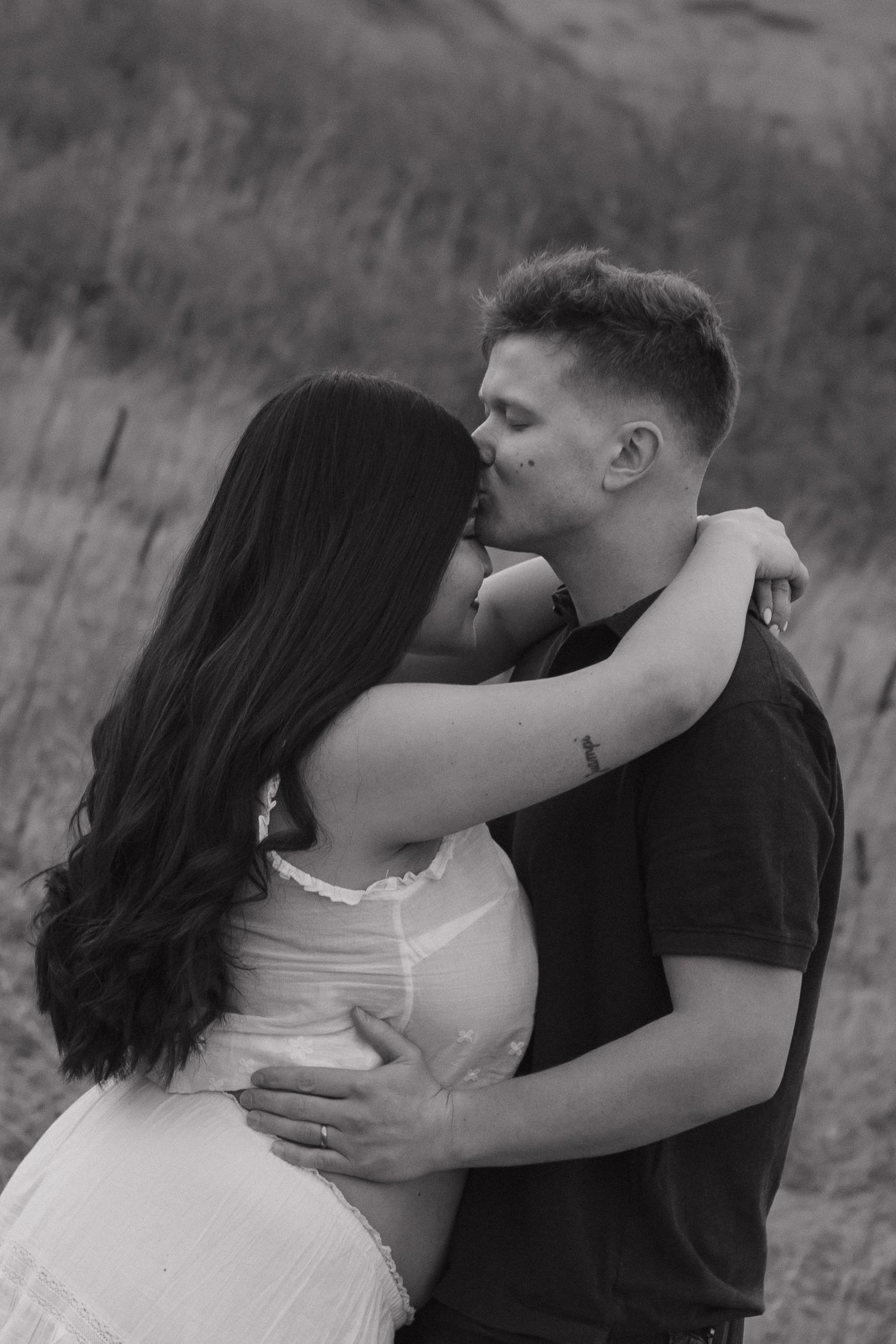 Expecting couple sharing an intimate moment outdoors during a natural and romantic maternity photography session