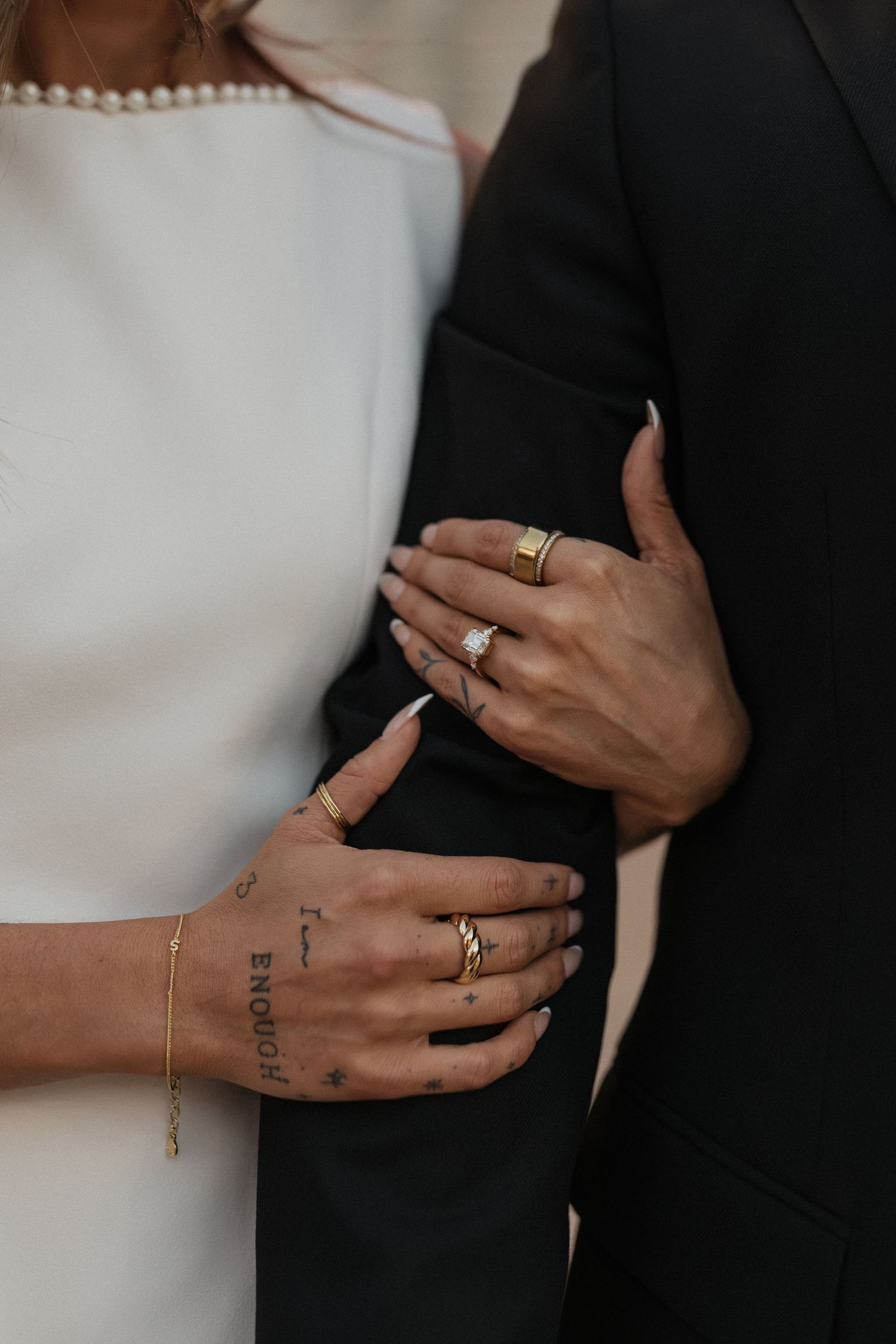 Close-up of a couple holding each other, showing their hands and wedding rings