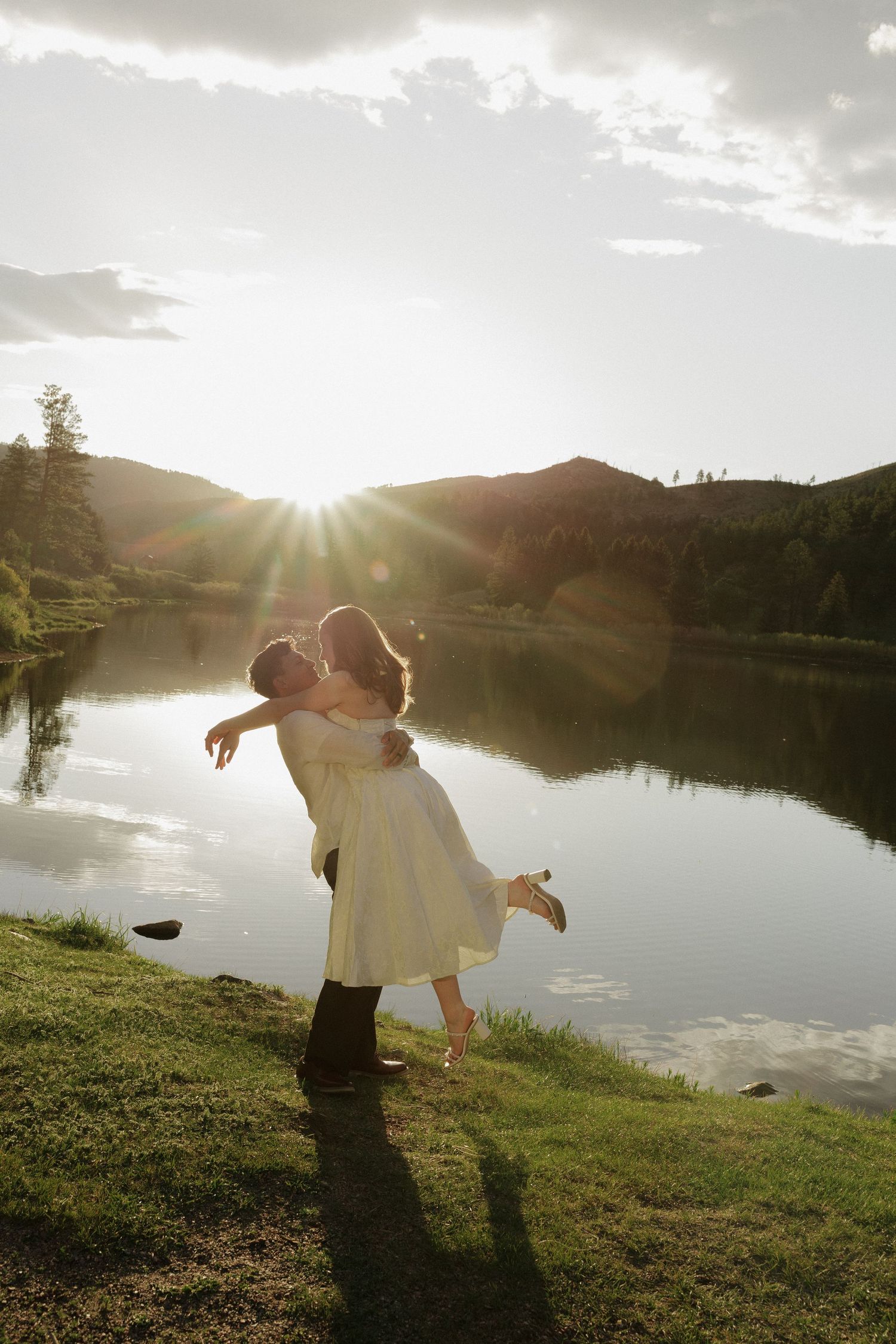 Couple dancing together beside a mountain lake at sunset during a romantic couples photography session