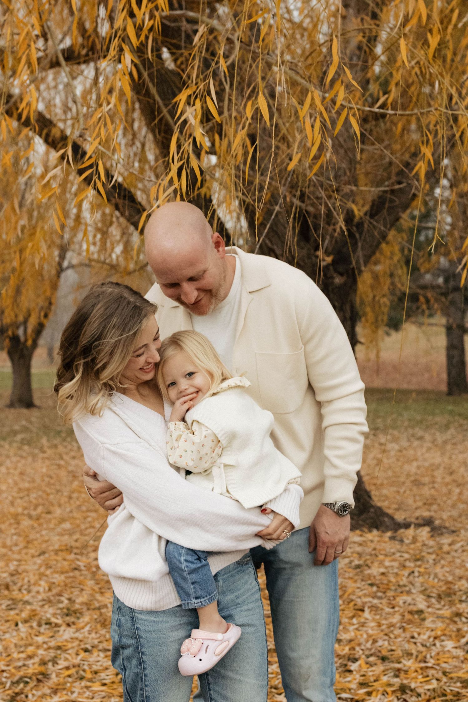 Famili embracing outdoors surrounded by golden autumn foliage during a photography session
