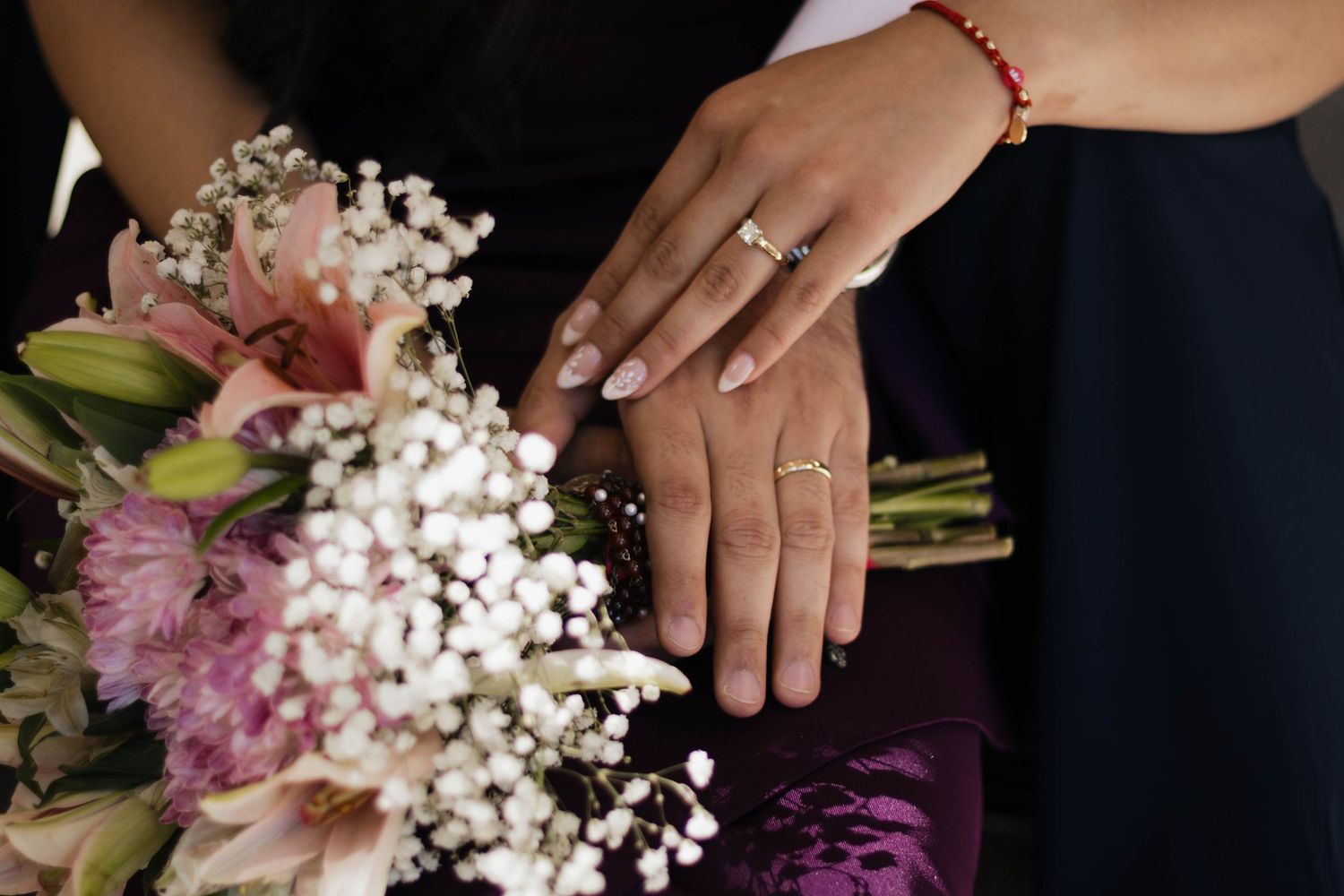 Engaged couple holding hands with their wedding rings and bouquet during an intimate engagement session