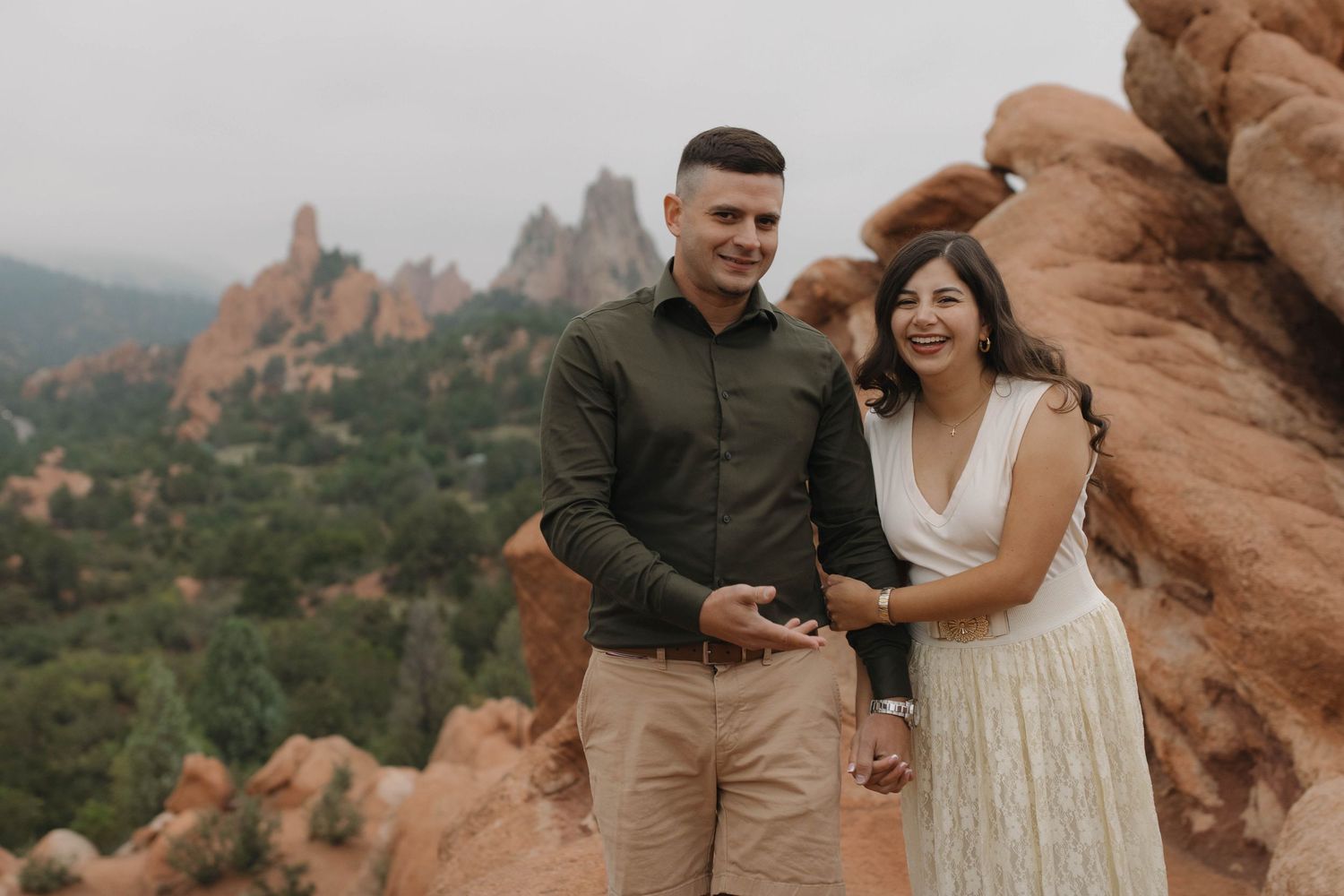 Couple walking and smiling together among dramatic red rock formations during an outdoor couples photography session